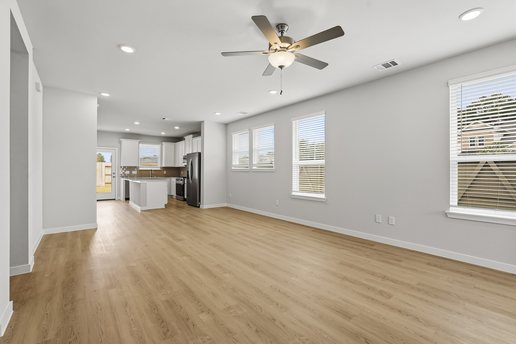 A large empty room with a wood floor and a ceiling fan.