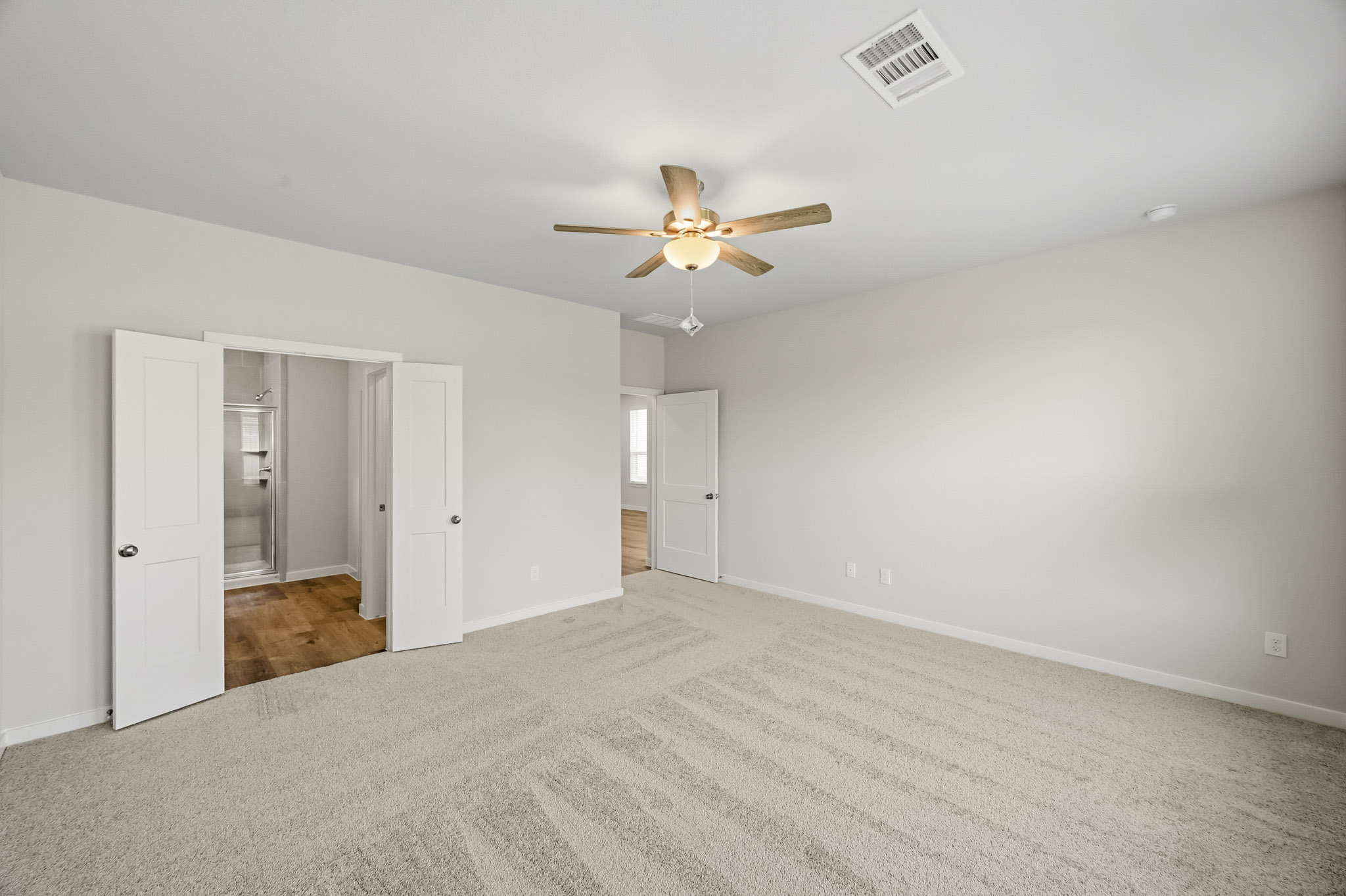 A room with a ceiling fan and white doors.