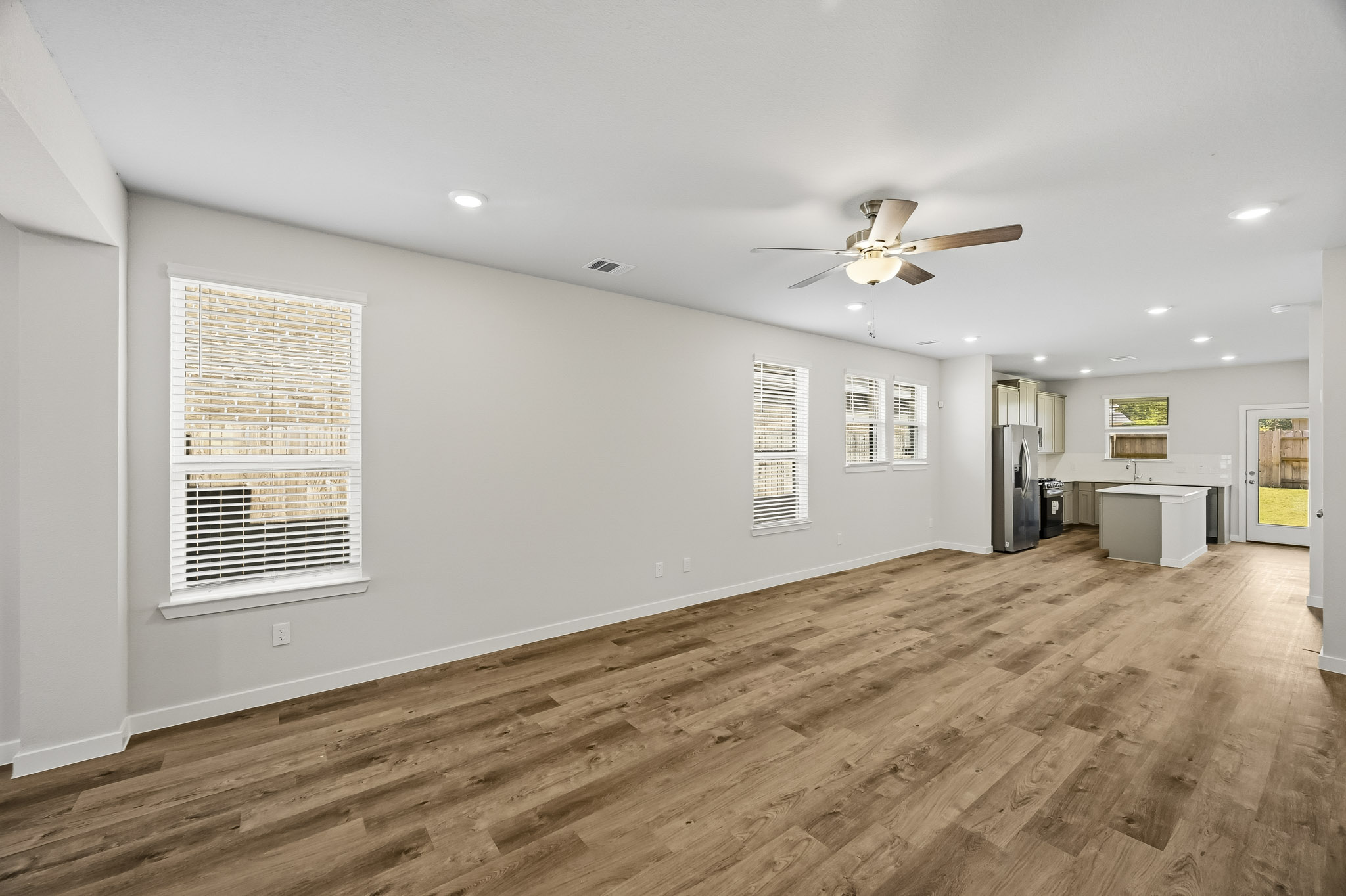 A large empty room with a wood floor and a ceiling fan.