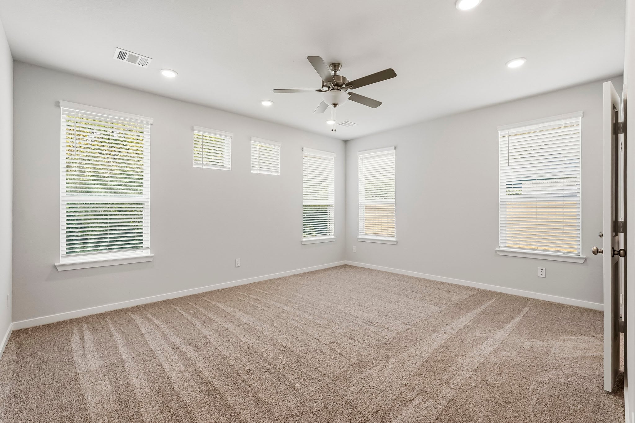 A room with a ceiling fan and a carpet.