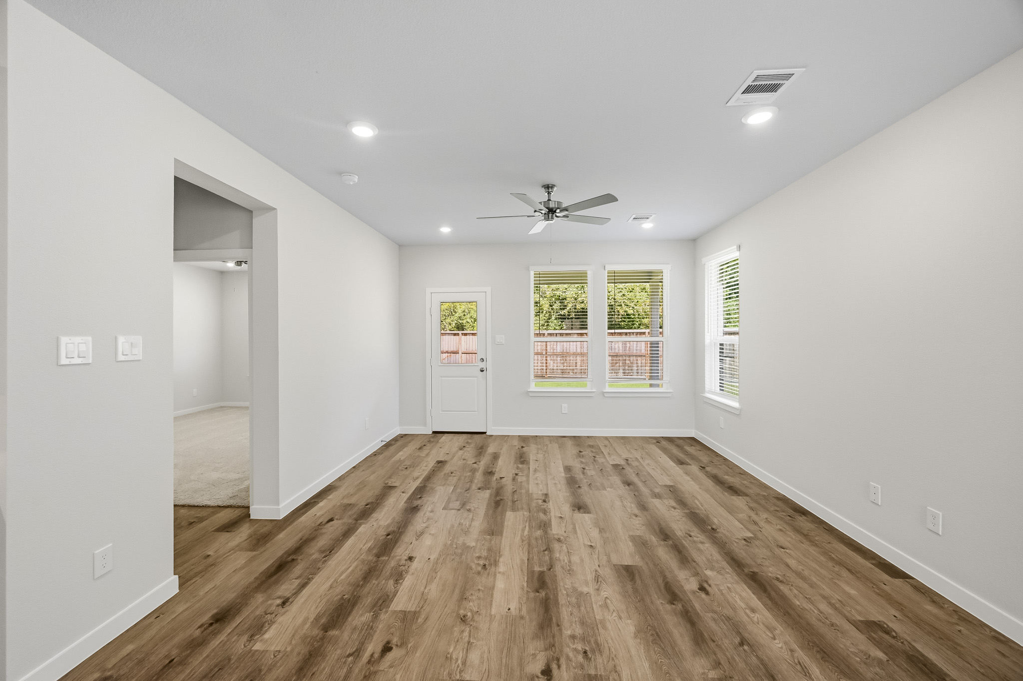 A room with a wood floor and a wood floor with a fan.