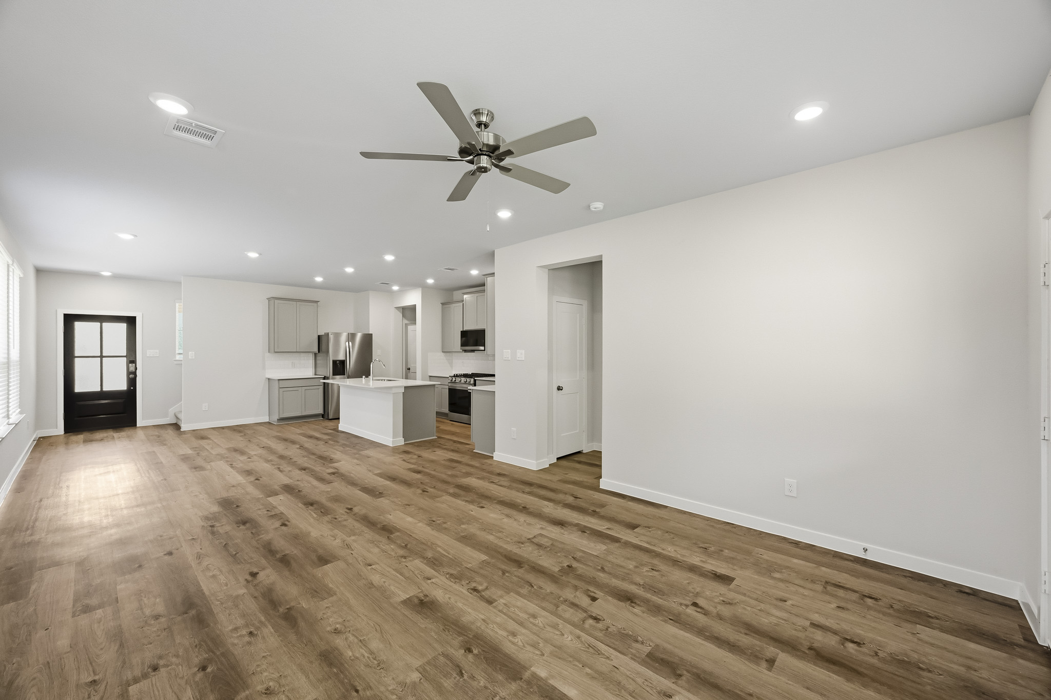 A large empty room with a ceiling fan and a wood floor.
