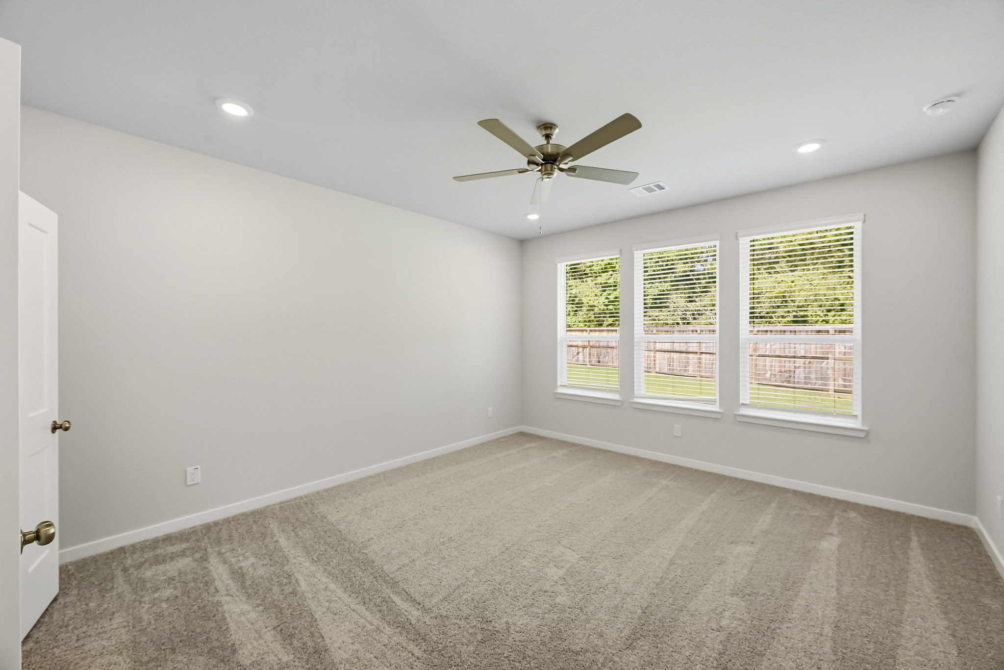 A room with a ceiling fan and windows.