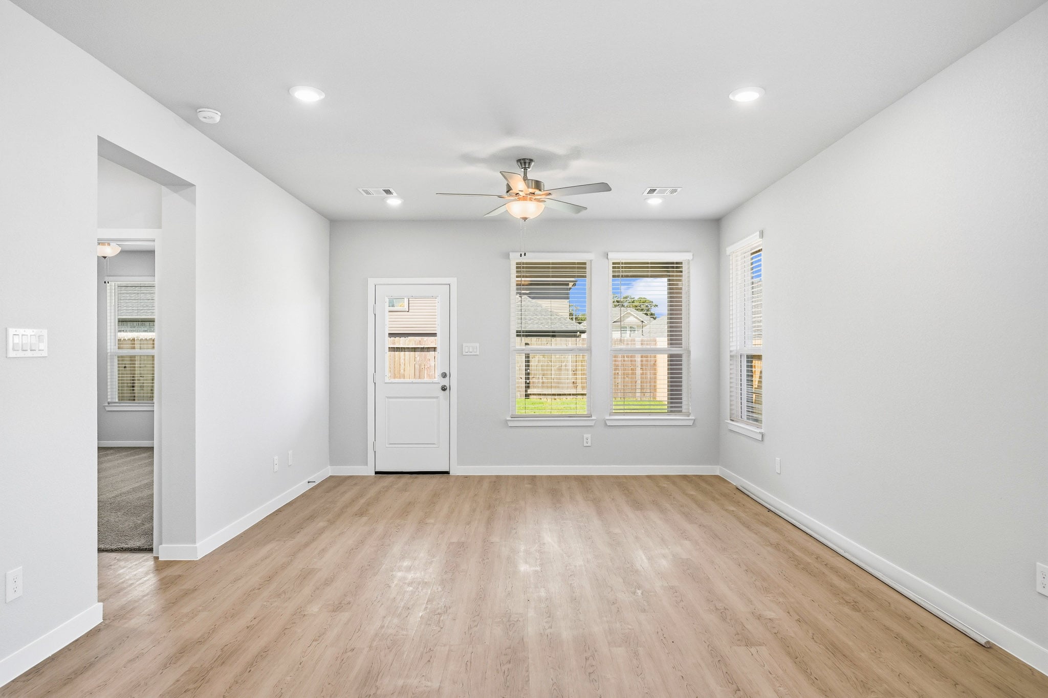 A room with a wood floor and a wood floor with a ceiling fan.
