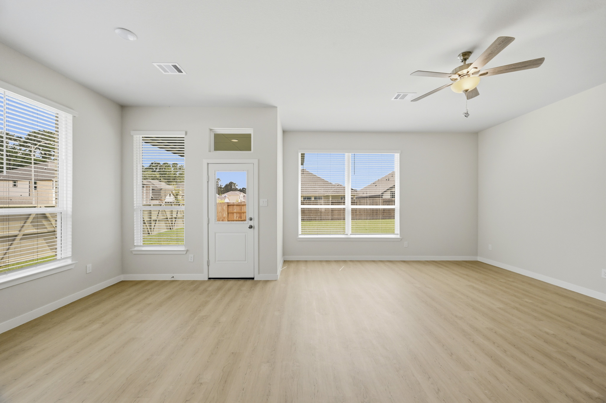 A room with a fan and a wood floor.
