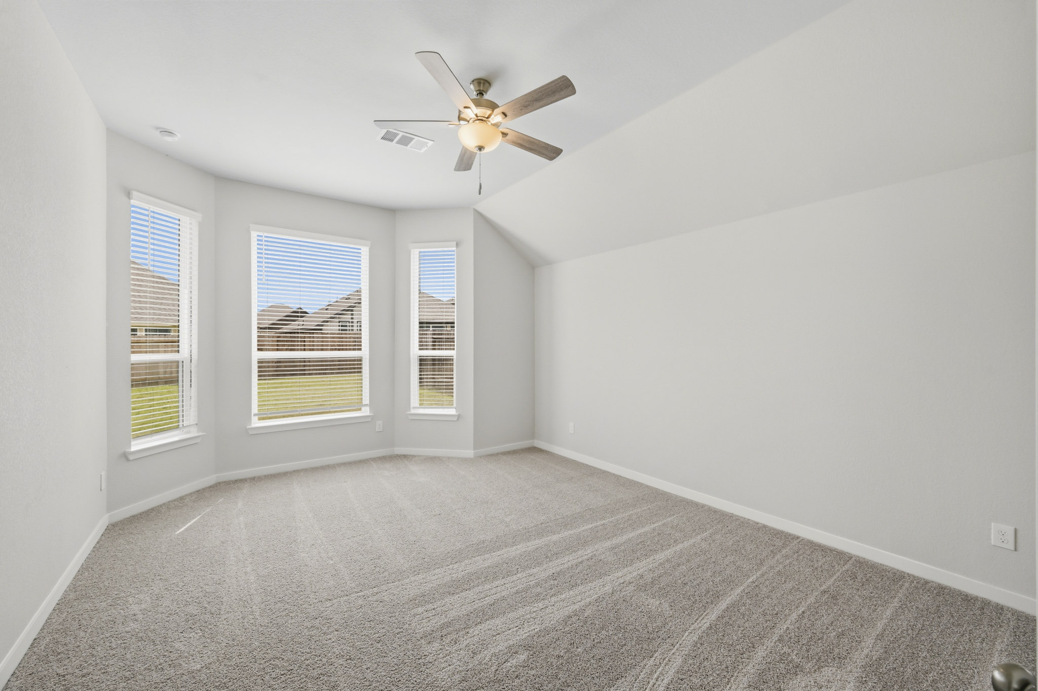 A room with a ceiling fan and windows.