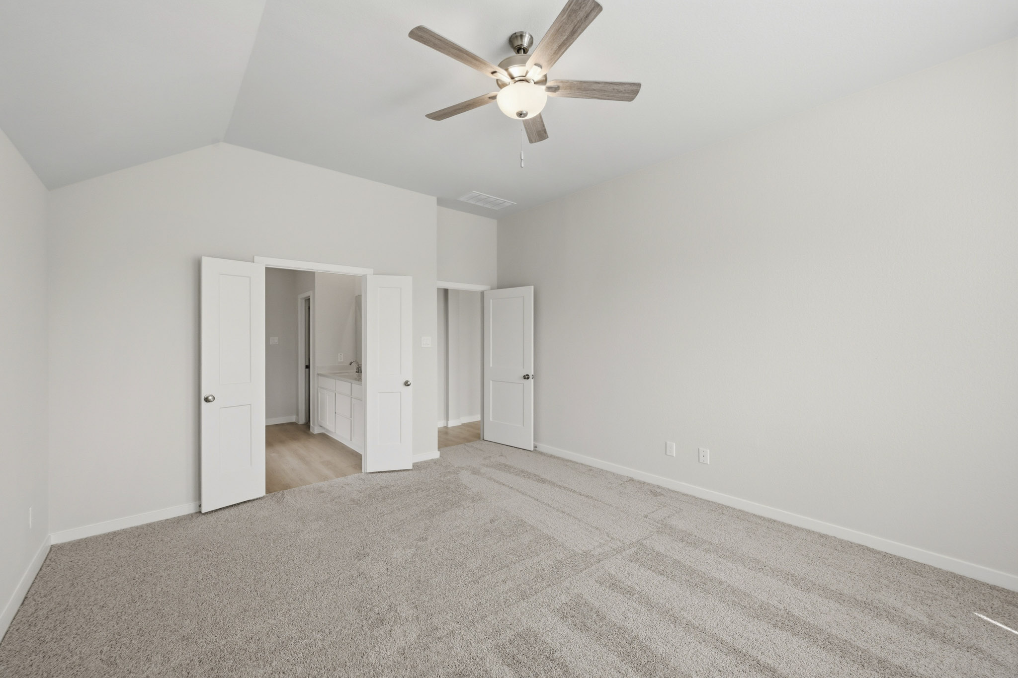 A room with a ceiling fan and white doors.