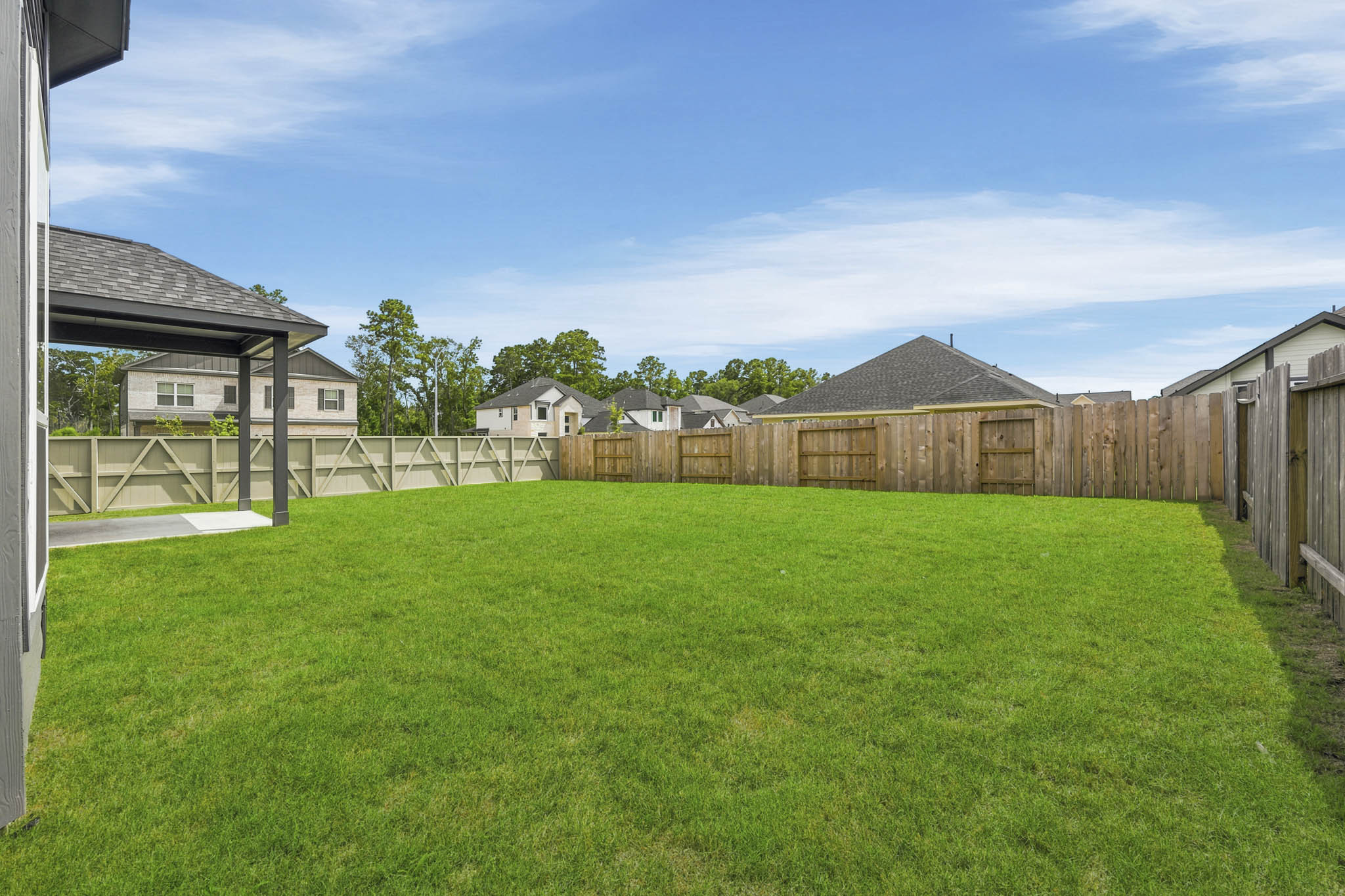 A grassy yard with a fence and buildings in the background.