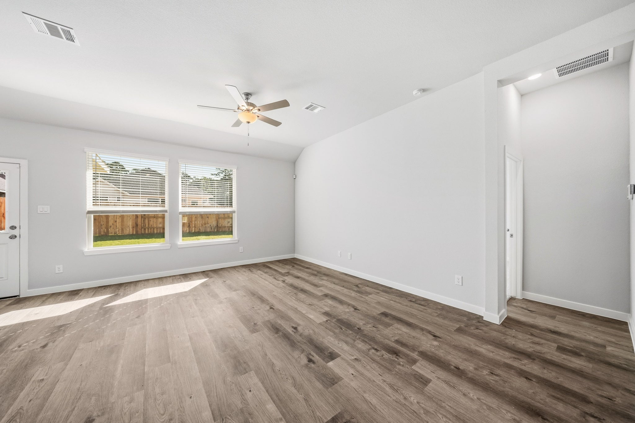 A room with a wood floor and a ceiling fan.