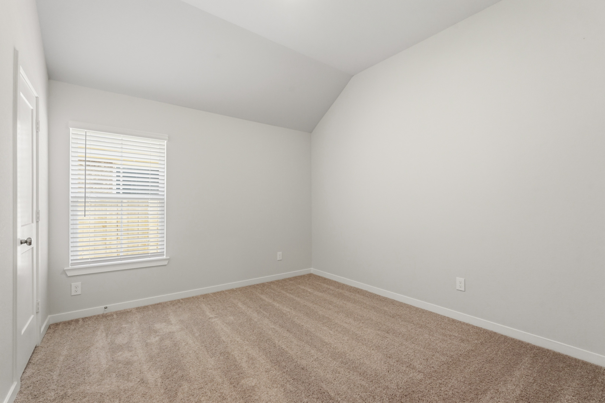 A room with a carpet and a window.