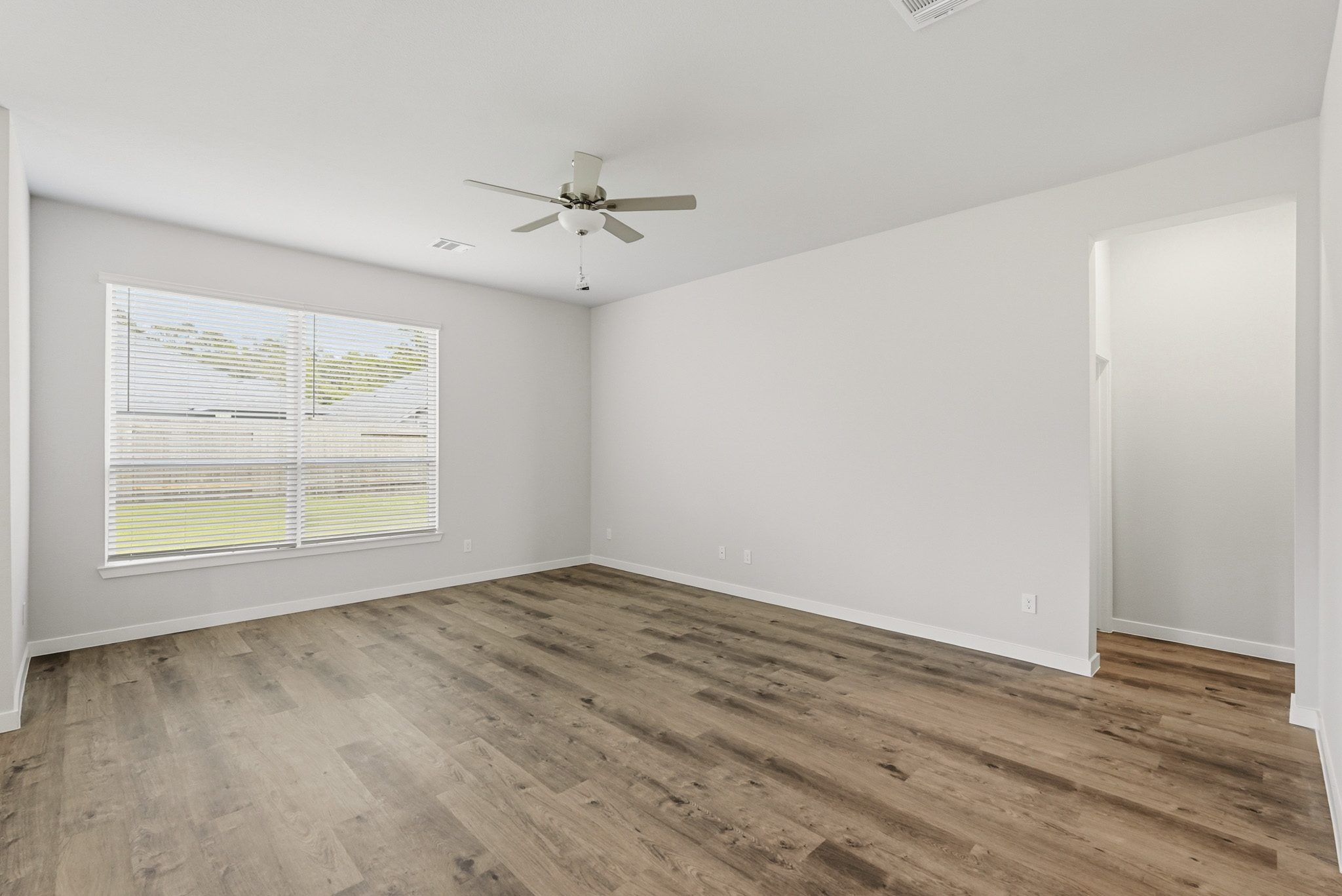 A room with a ceiling fan and wood floor.