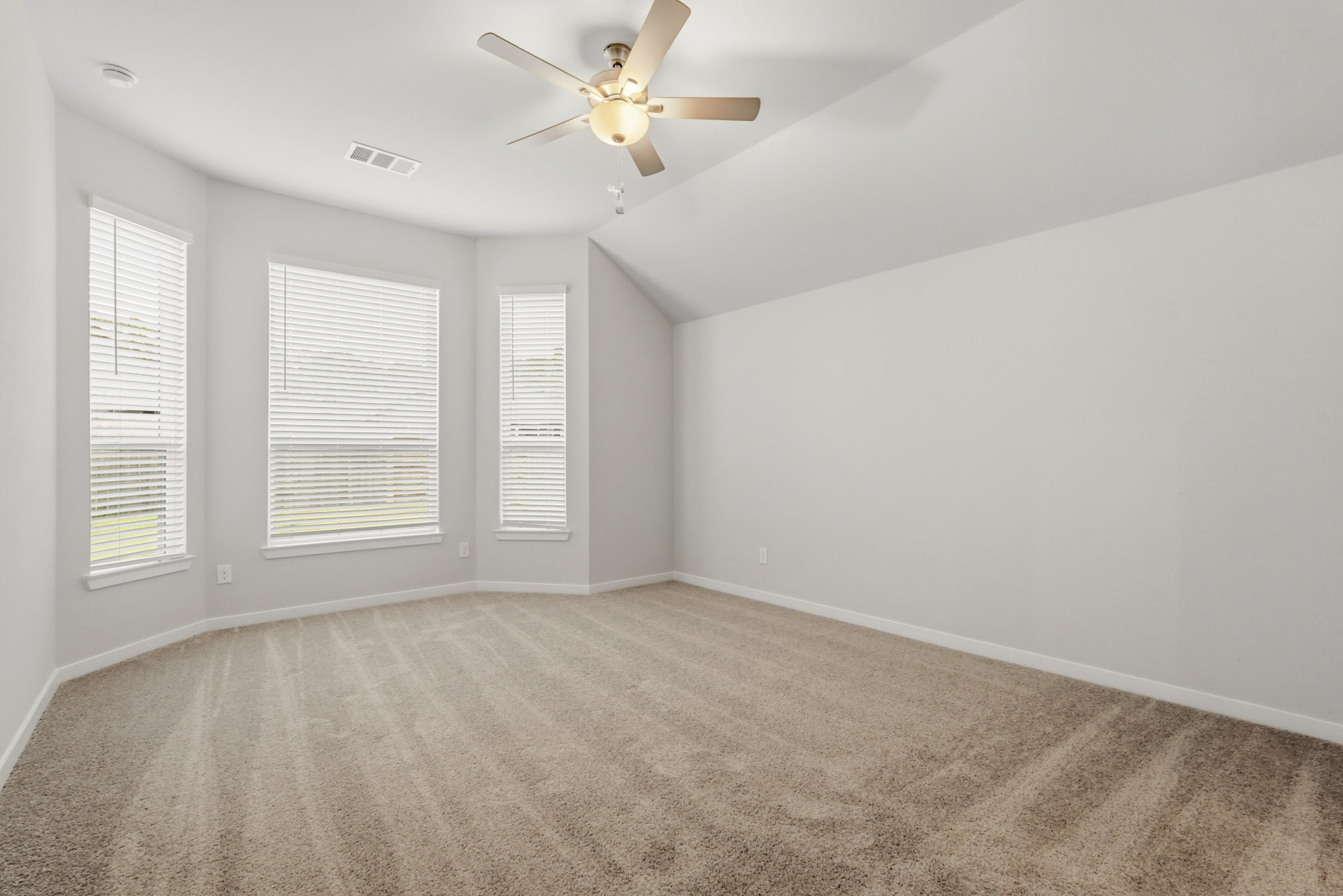 A room with a ceiling fan and a carpet.