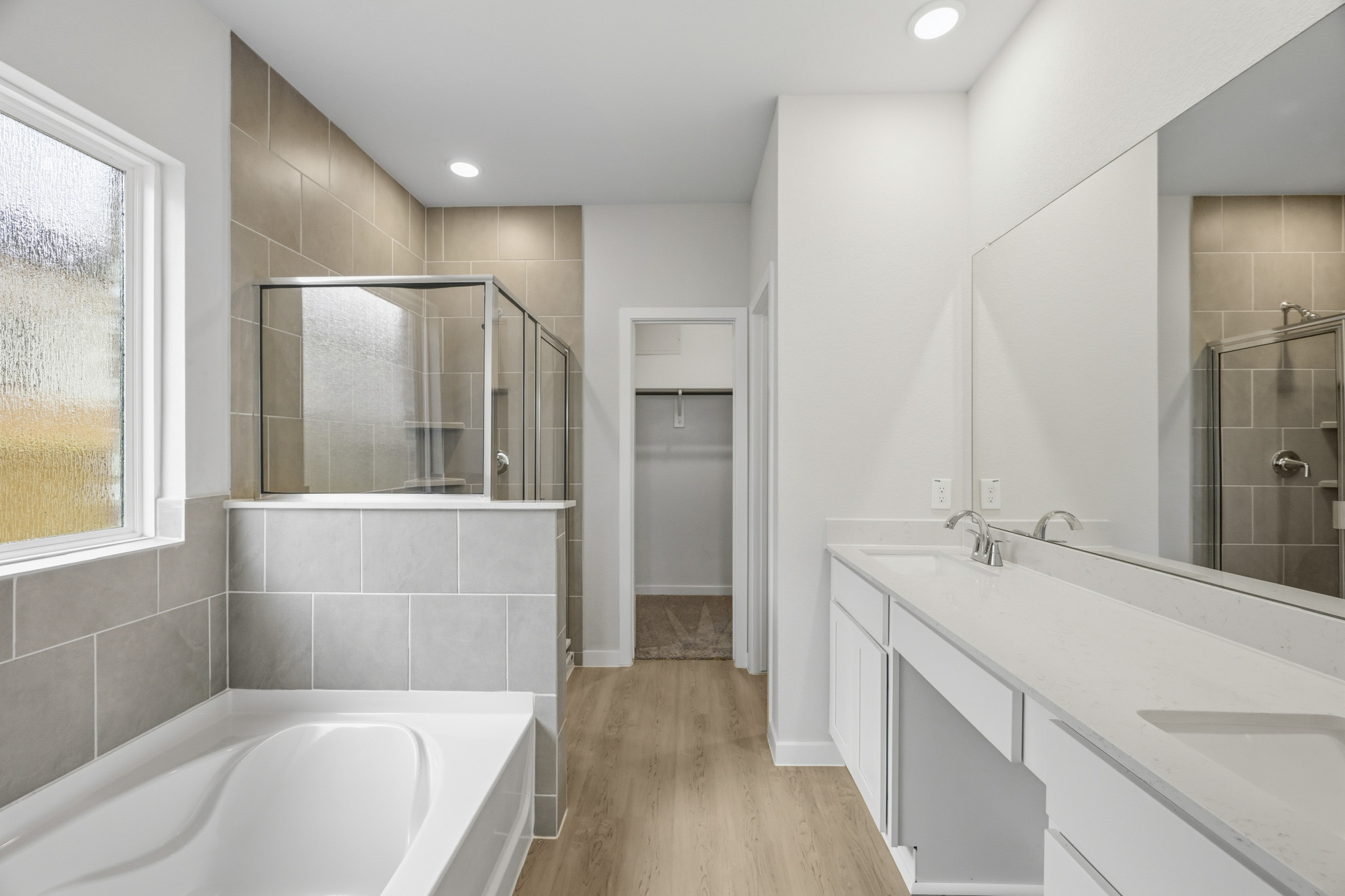 A bathroom with a tub sink and mirror.