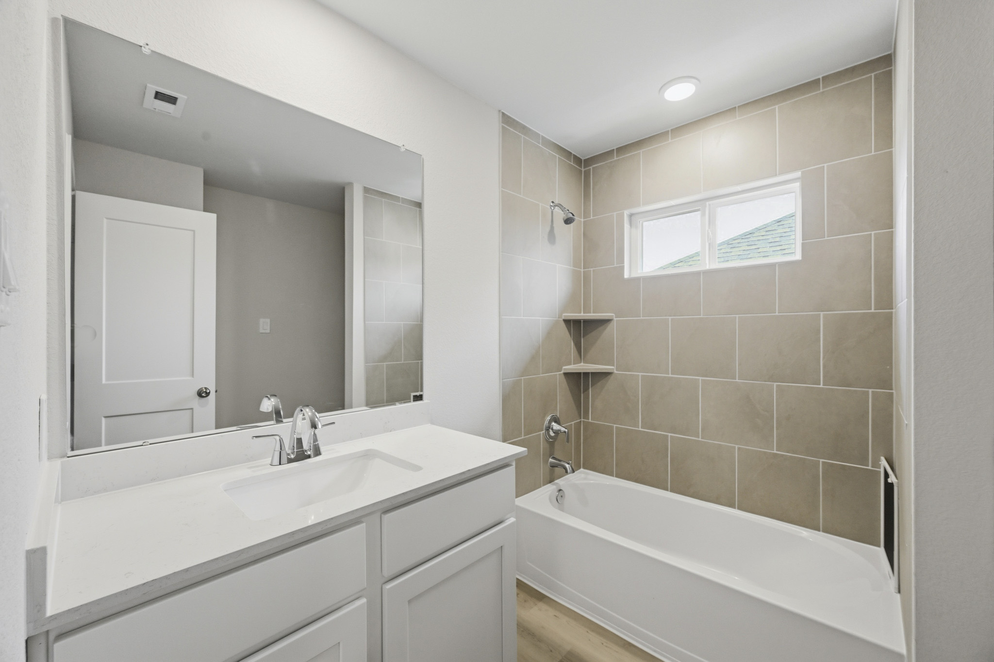 A bathroom with a tub sink and mirror.