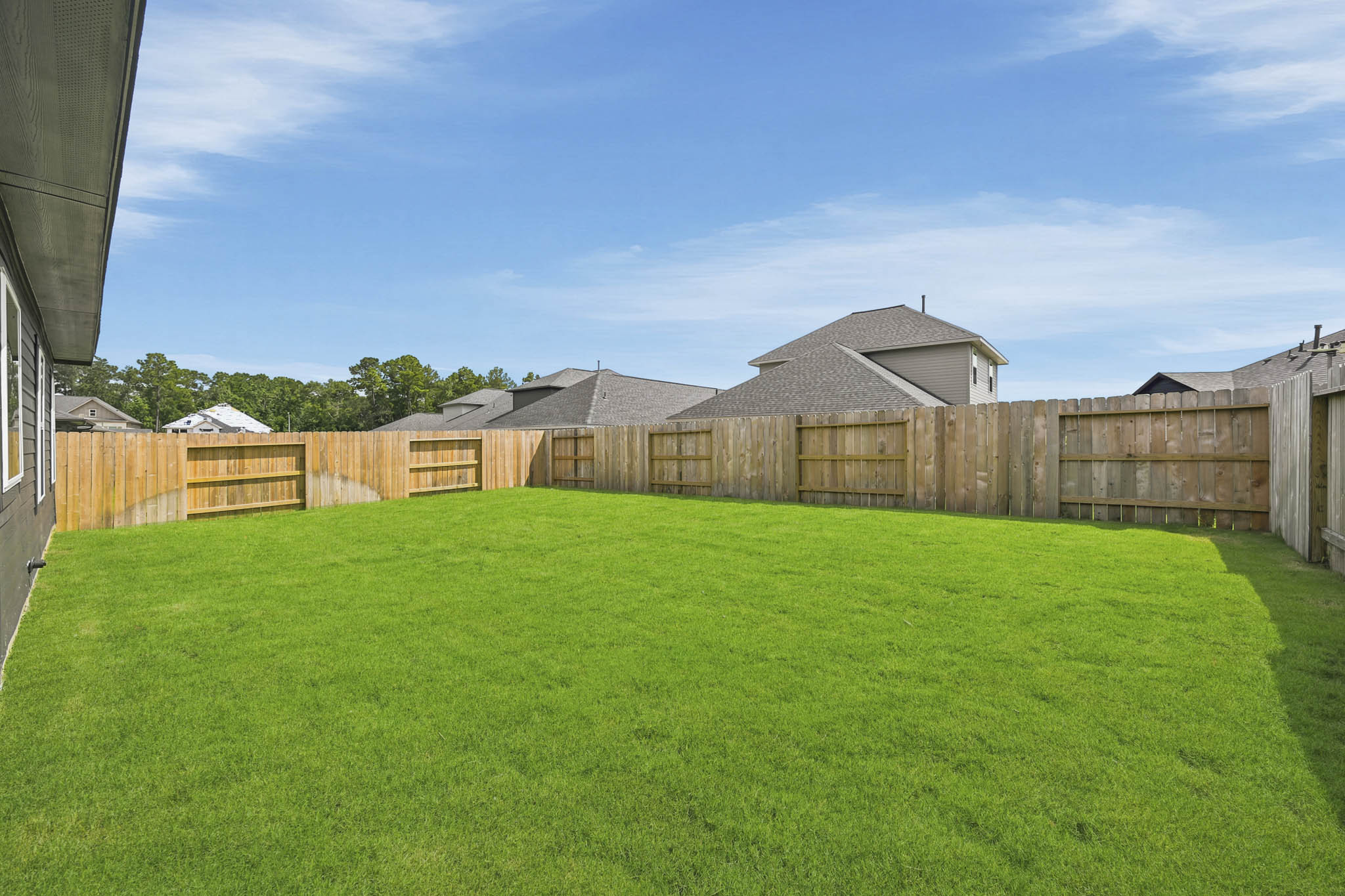 A fenced in yard with a house in the background.