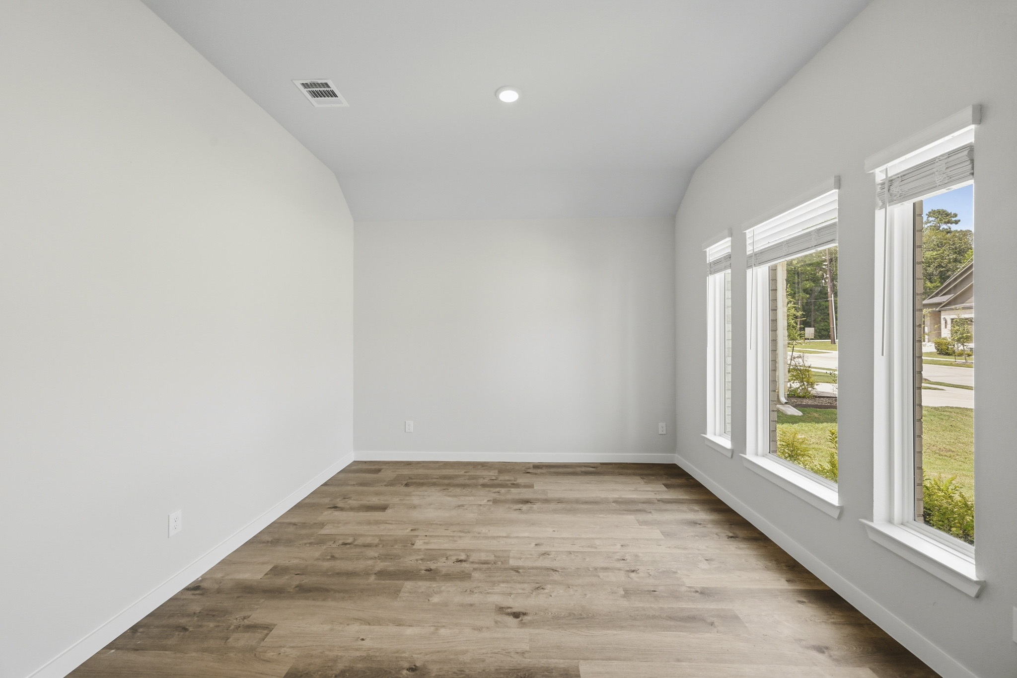 A room with a wood floor and windows.