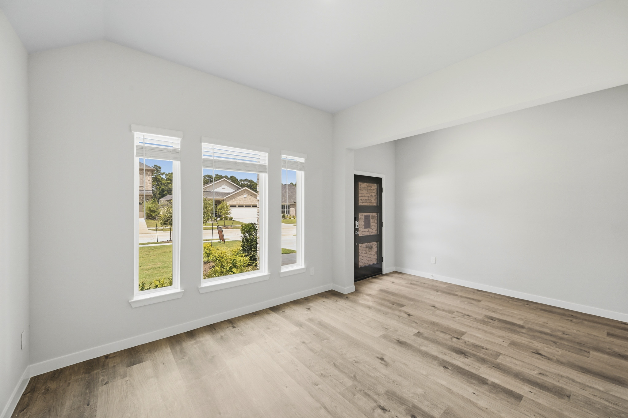 A room with a wood floor and a window with a view of the trees.