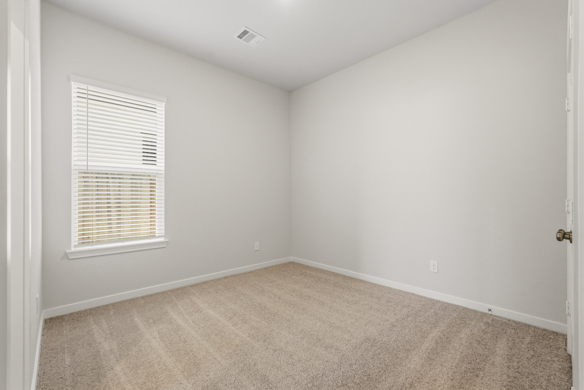 A room with a carpet and a window.