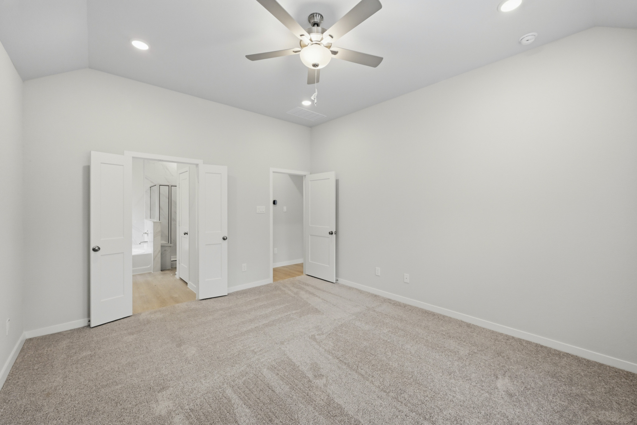 A room with a ceiling fan and white cabinets.