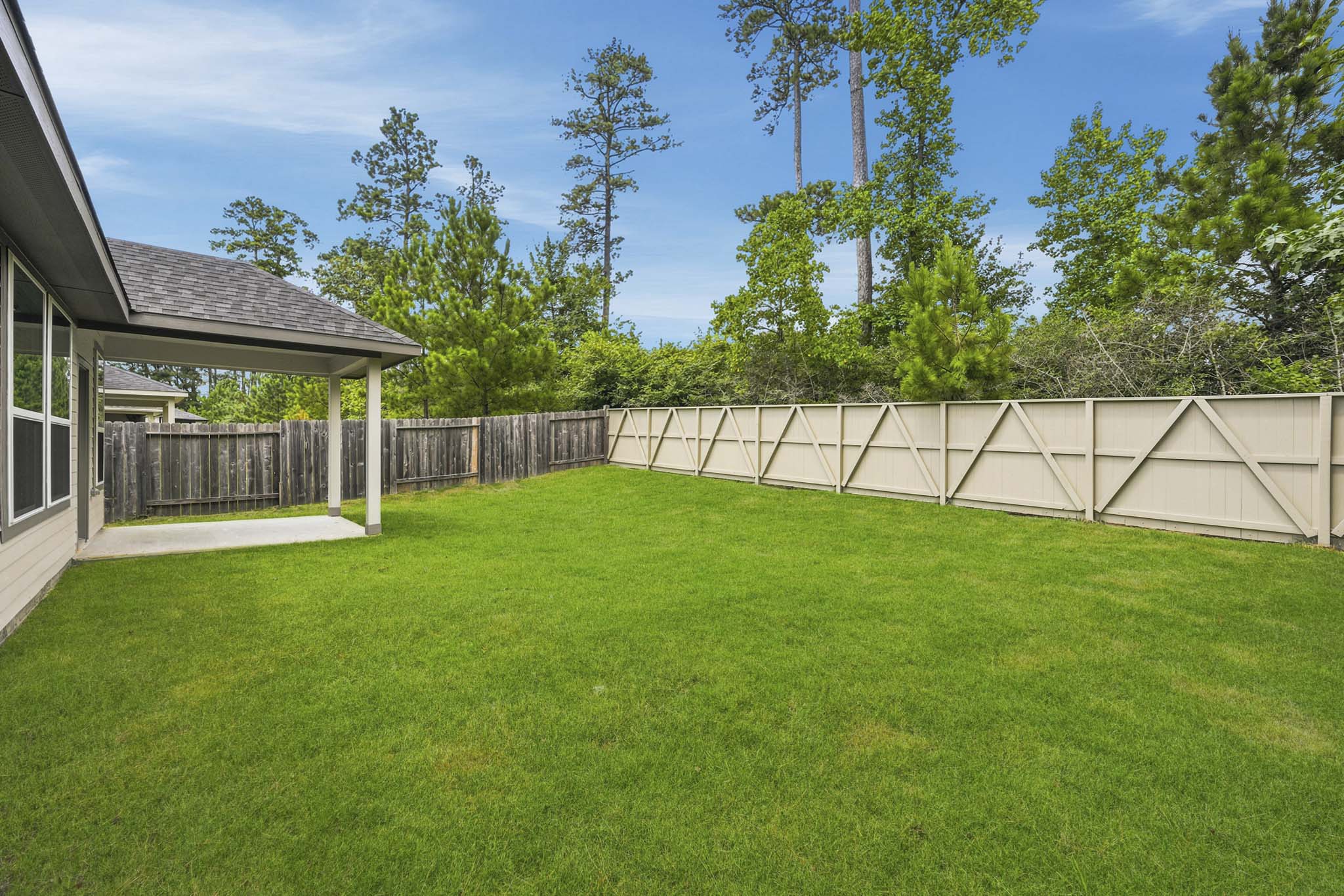 A fenced in yard with a house and trees in the background.