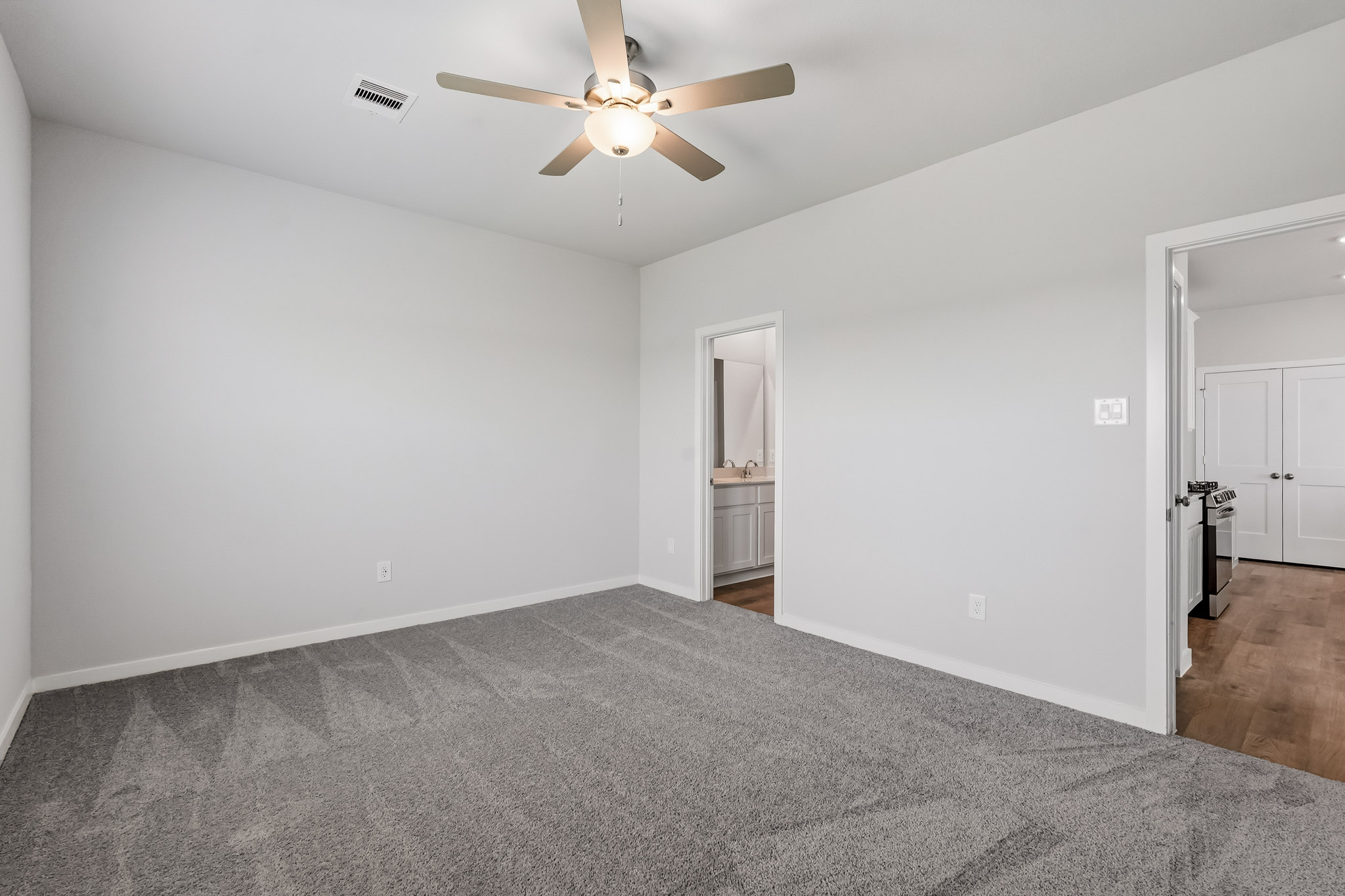 A room with a ceiling fan and a carpet.