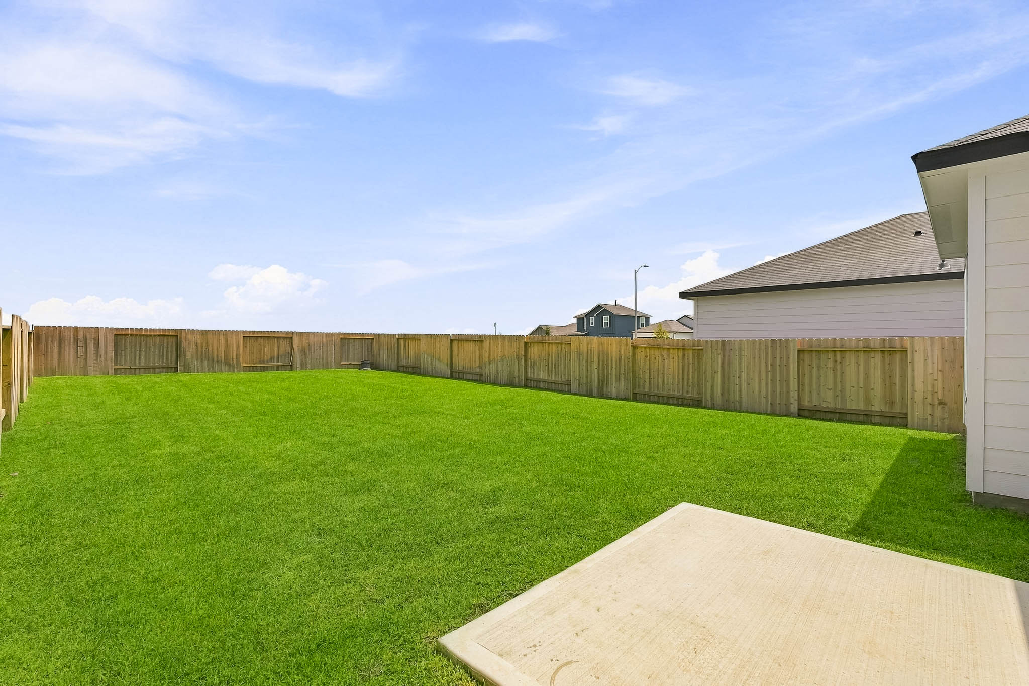 A fenced in yard with a wood fence and a house.