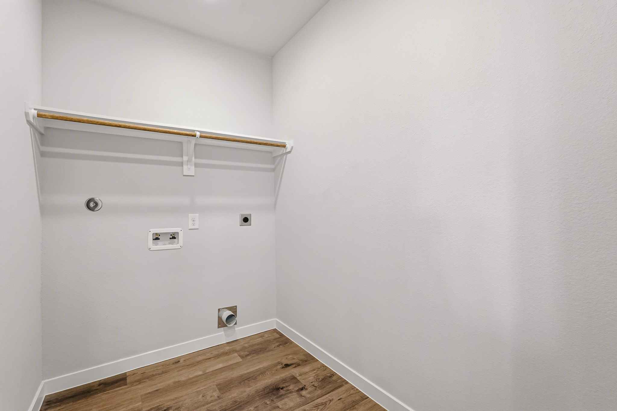 A white wall with a wood floor.
