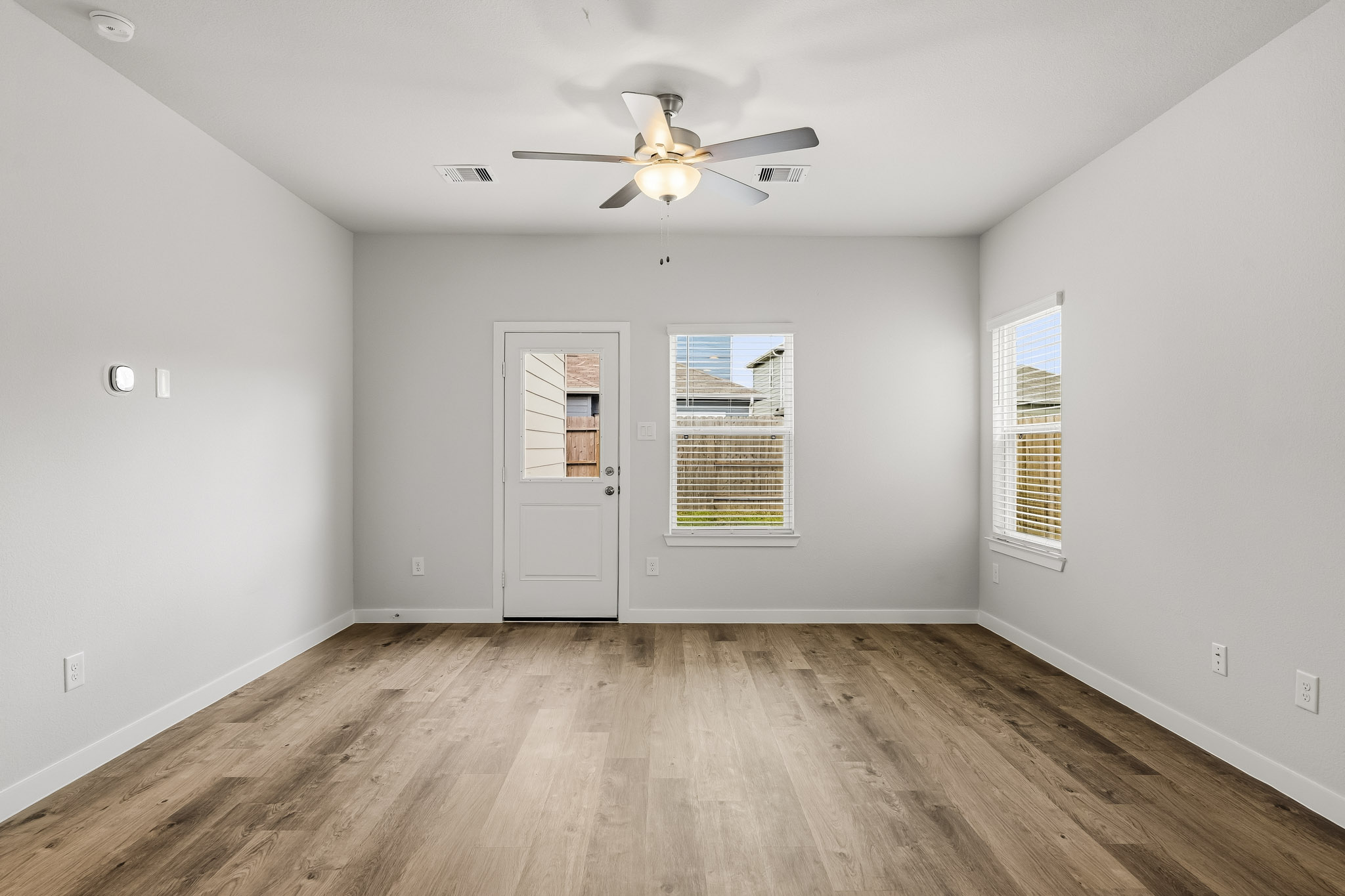A room with a ceiling fan and a wood floor.