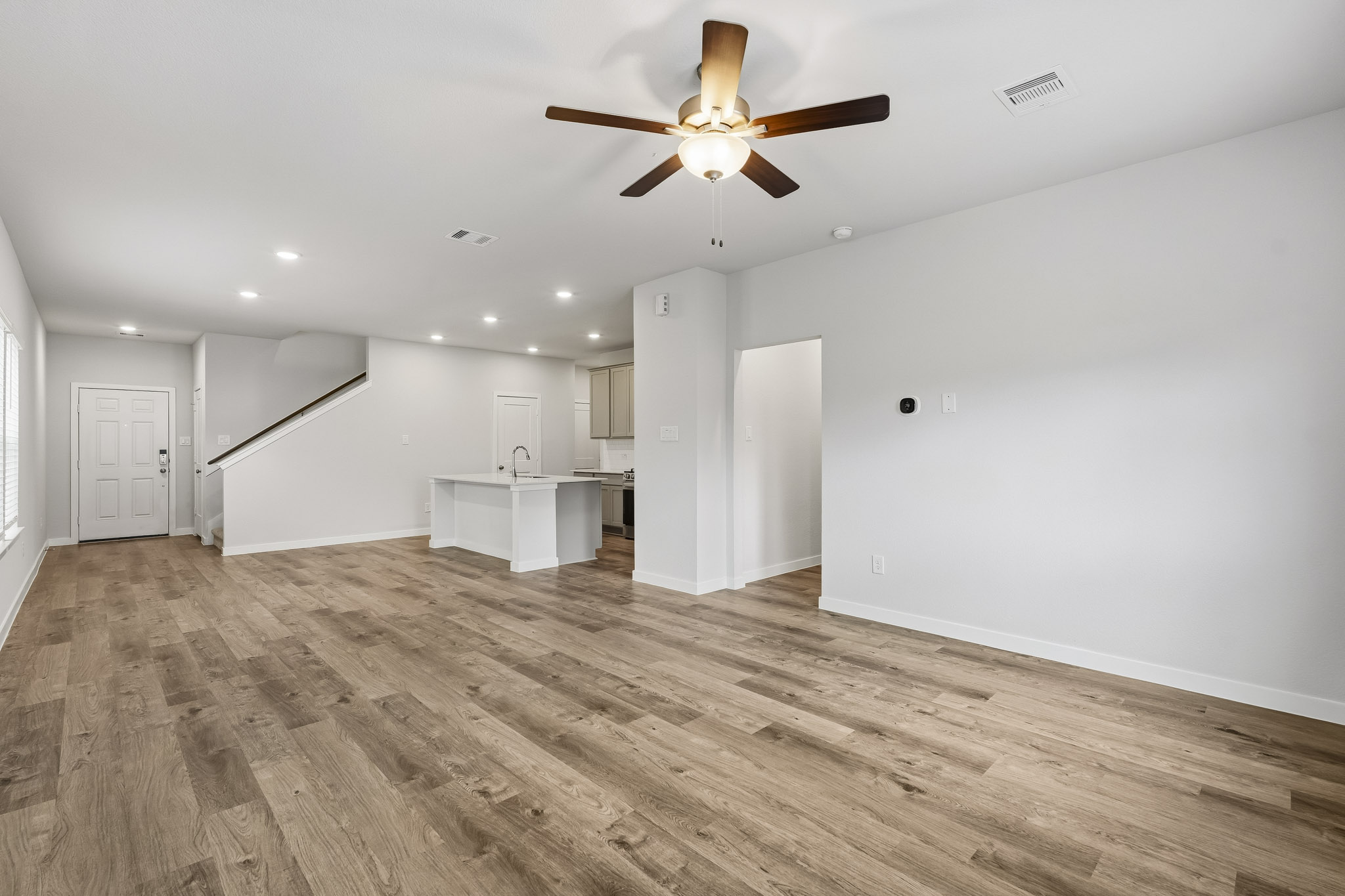A large empty room with a ceiling fan and a wood floor.