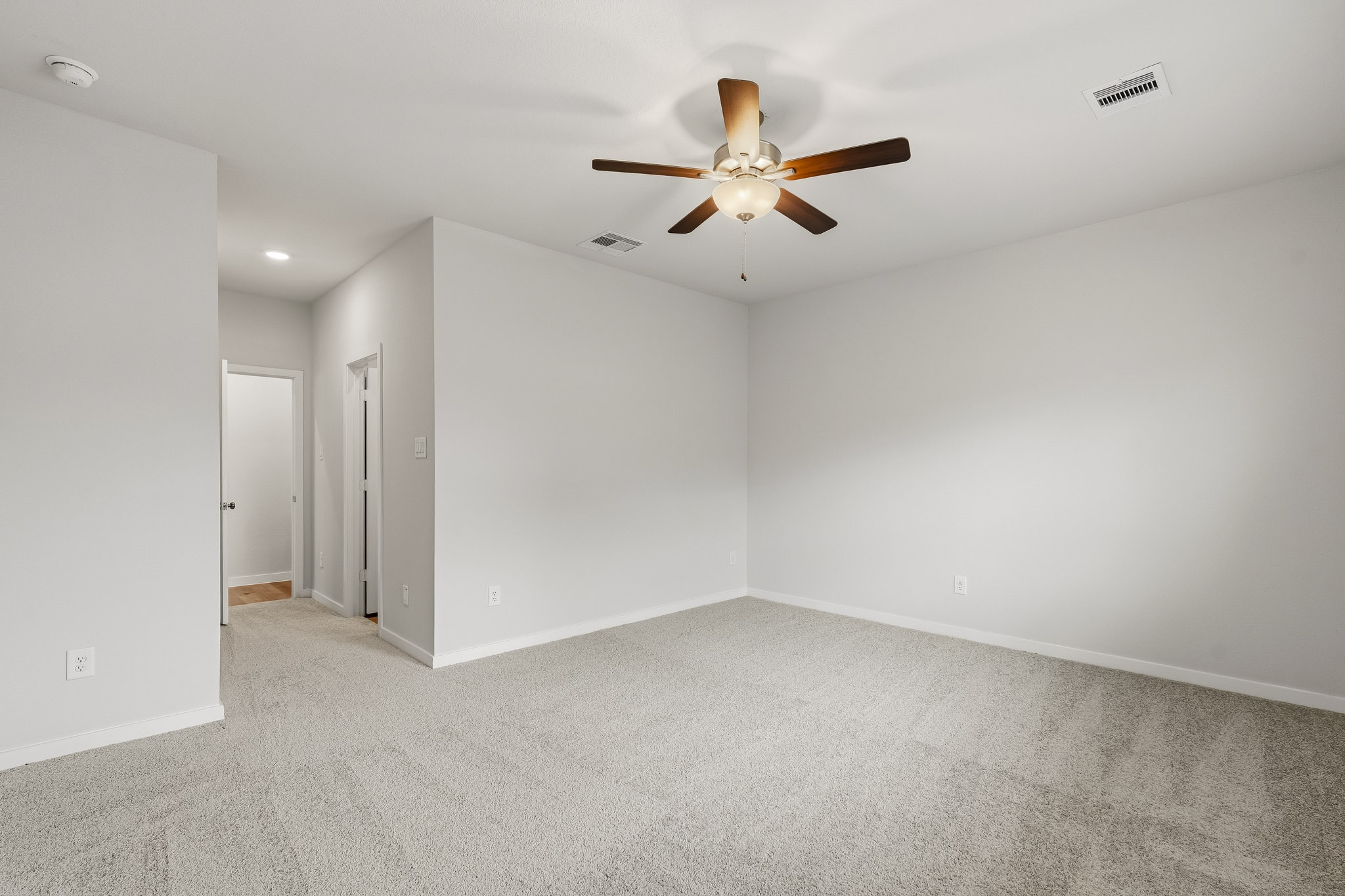 A room with a ceiling fan and white walls.