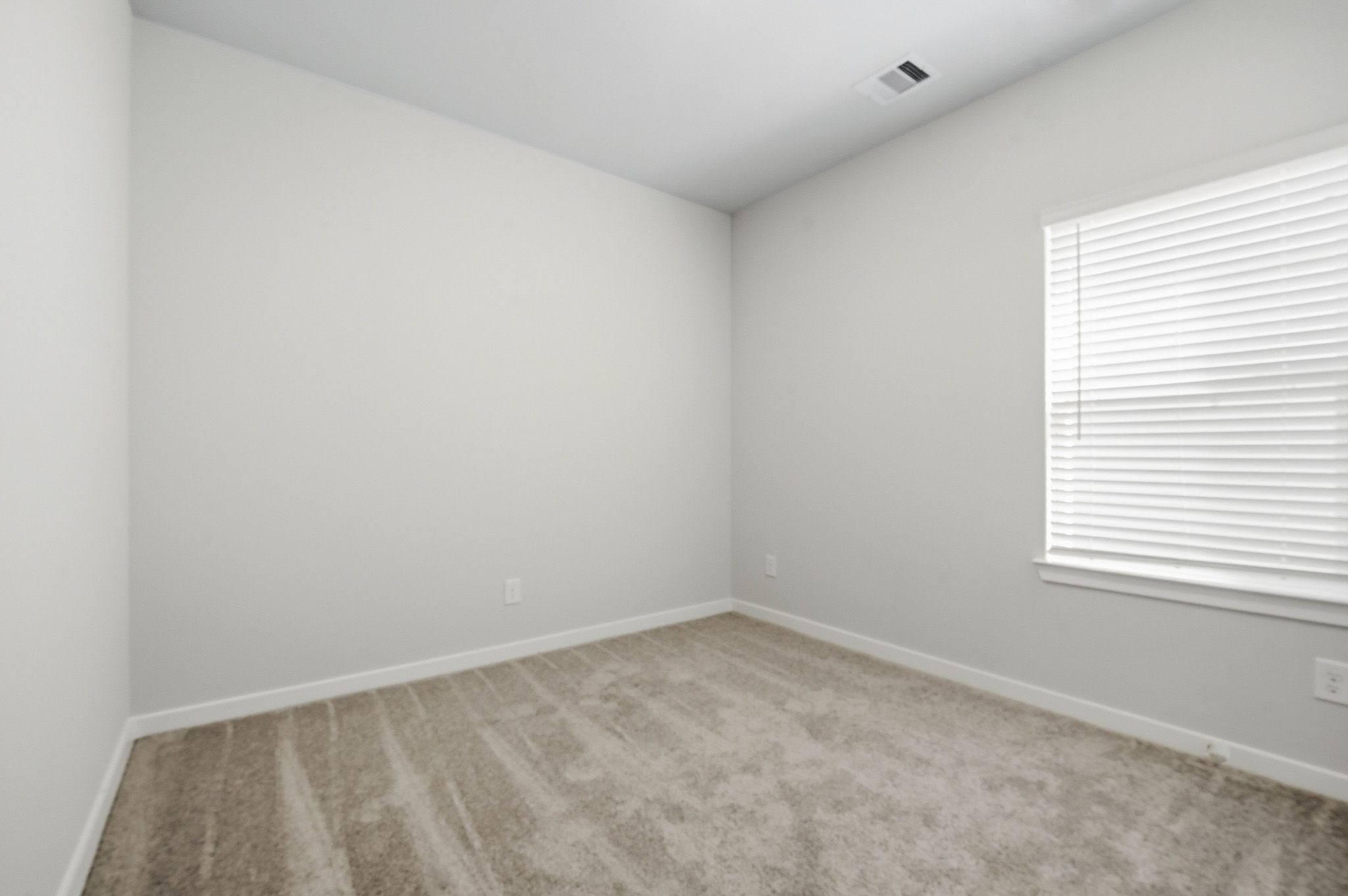 A room with a carpet and a window.