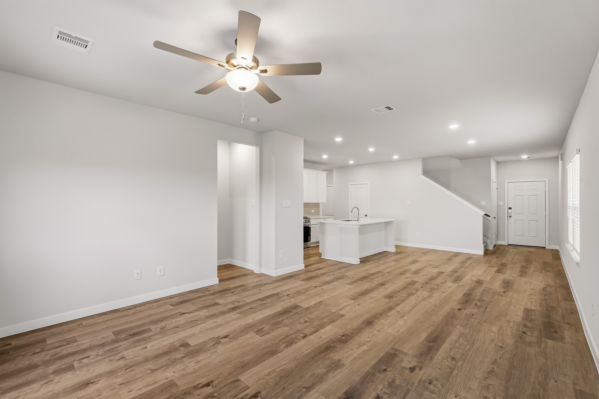 A room with a ceiling fan and a wood floor.