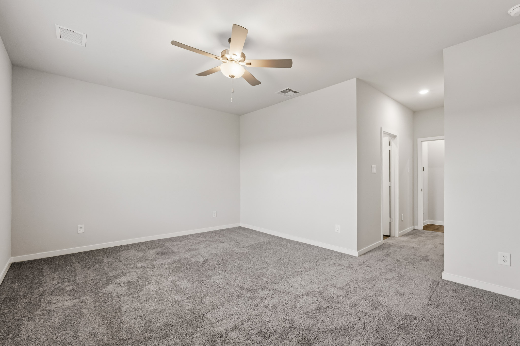 A room with a ceiling fan and carpet.