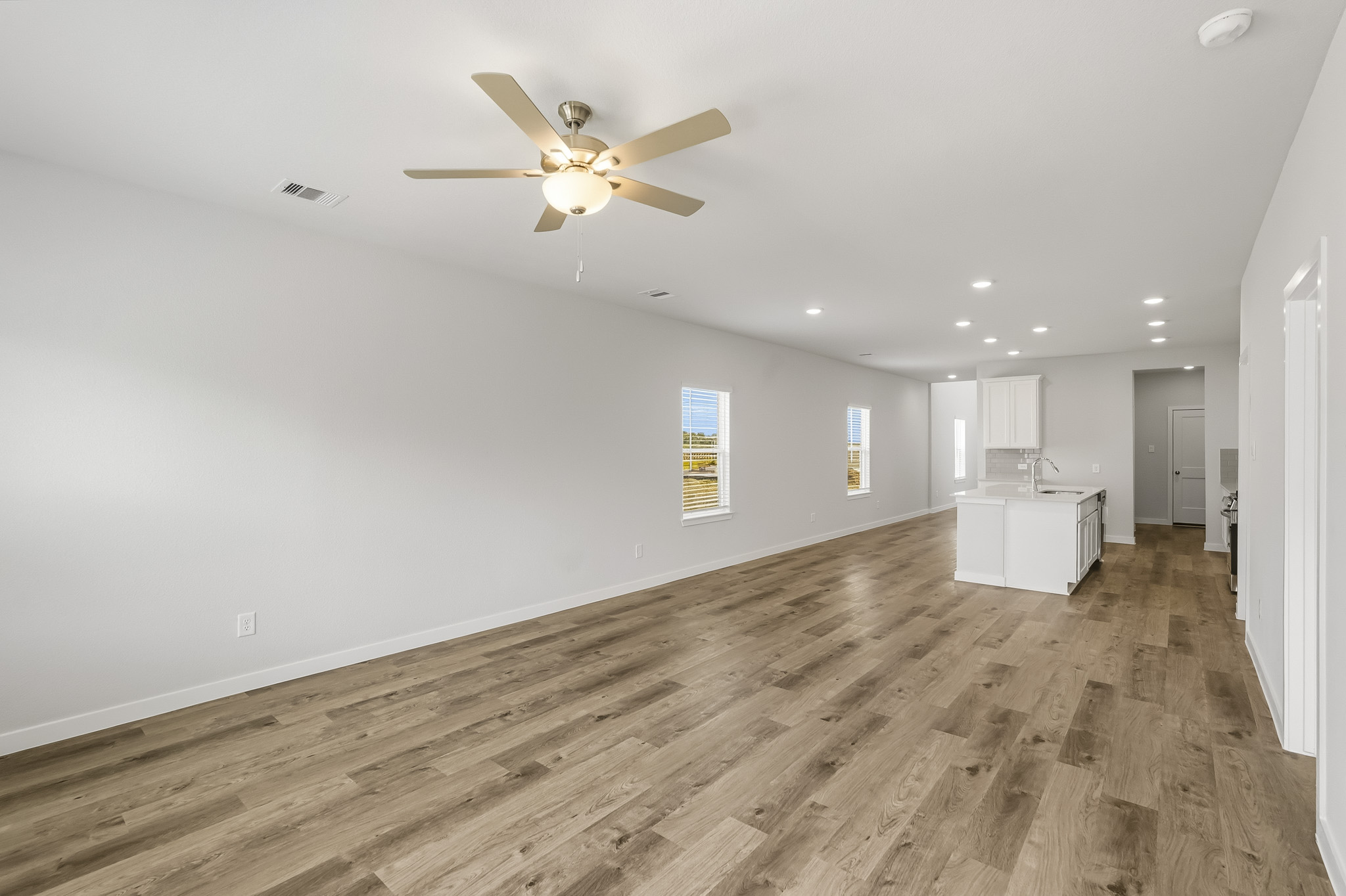 A room with a ceiling fan and a wood floor.