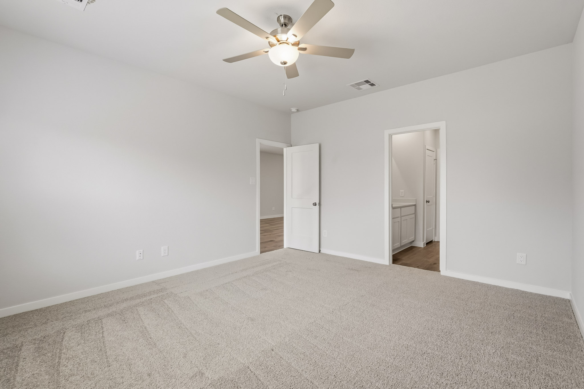 A room with a ceiling fan and a door.