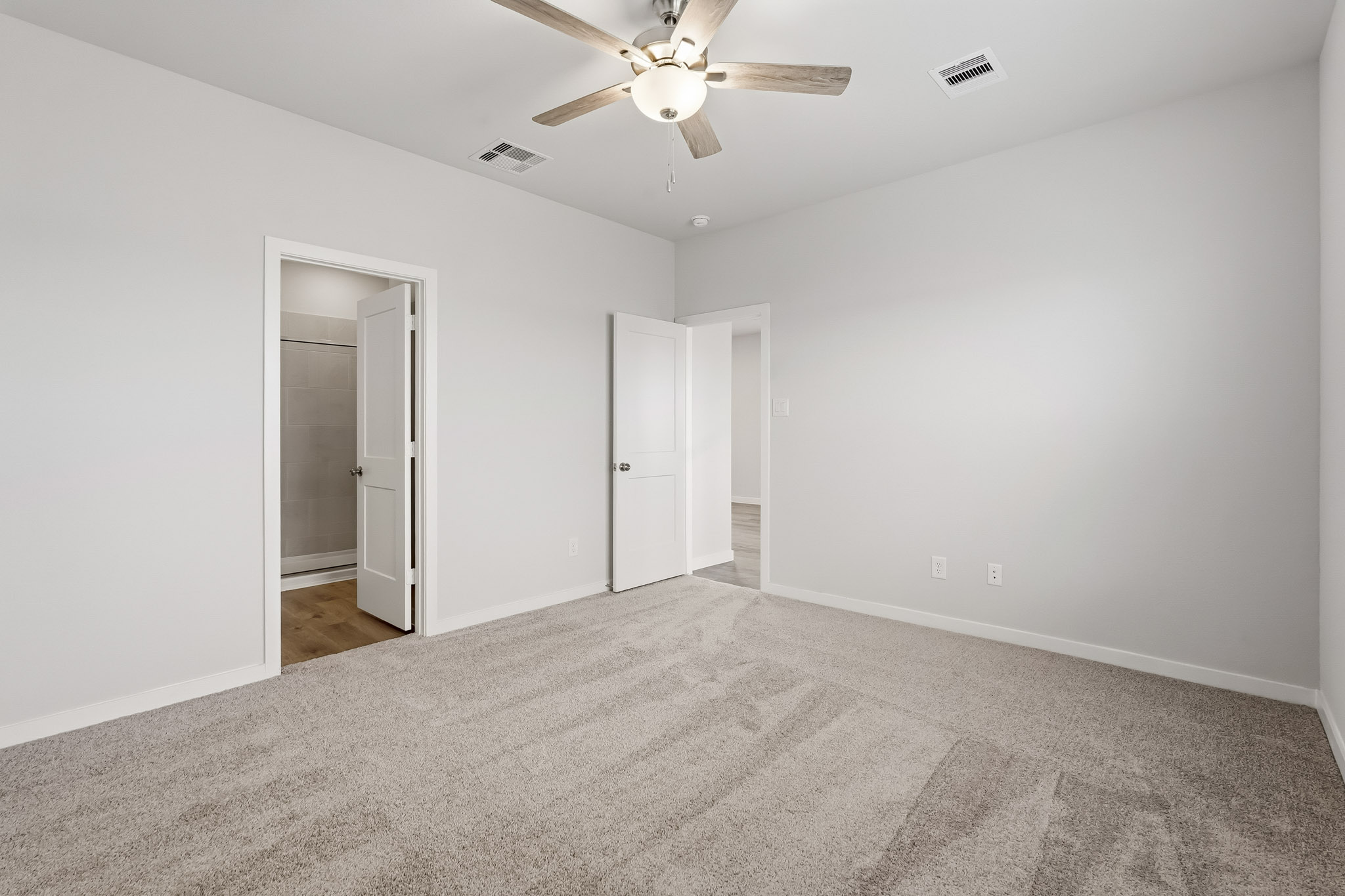 A room with a ceiling fan and a door.