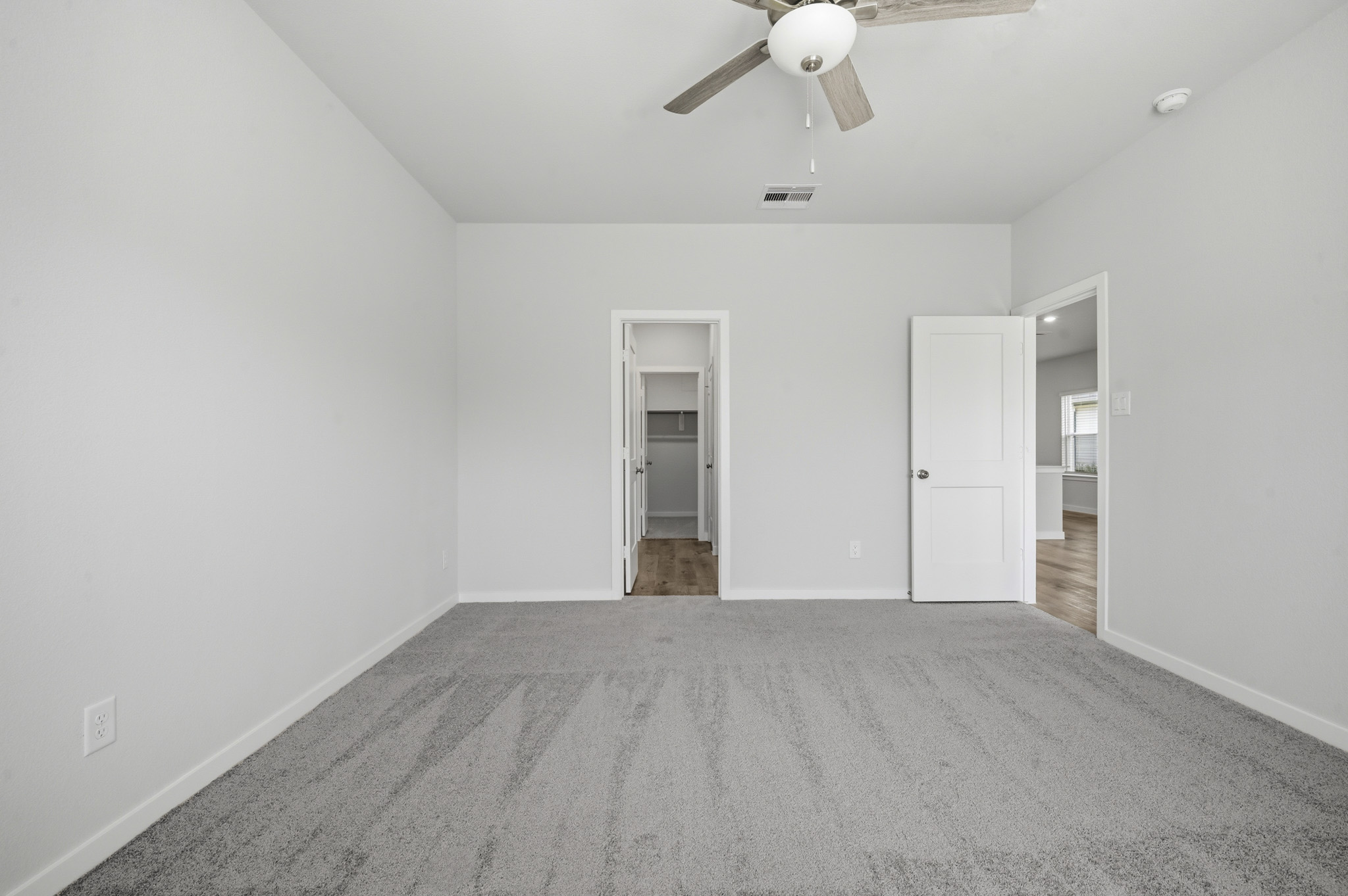A room with a ceiling fan and a door.