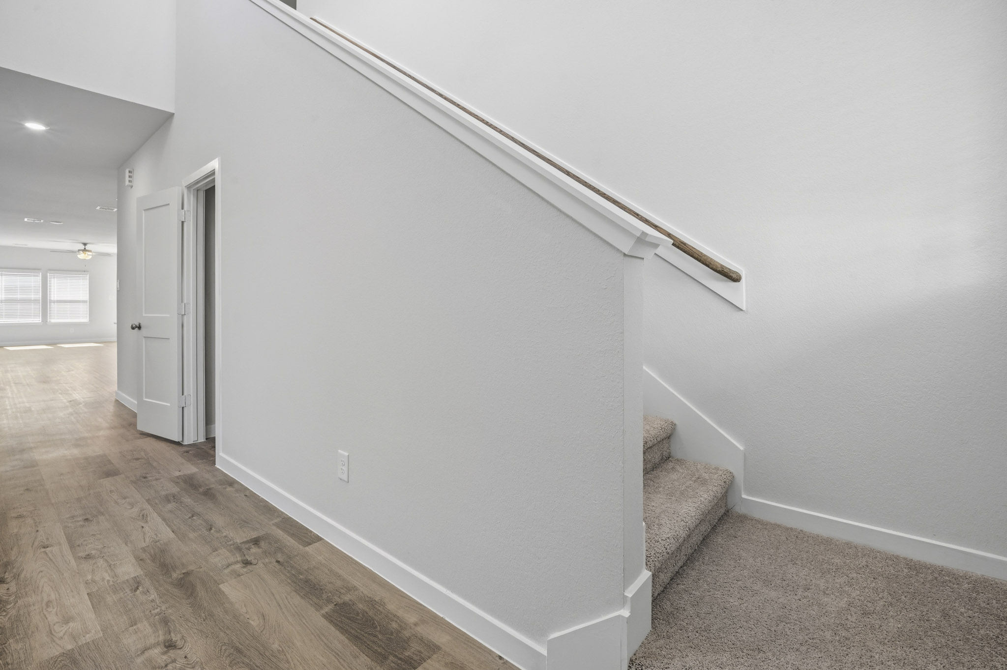 A room with a white wall and a wood floor.