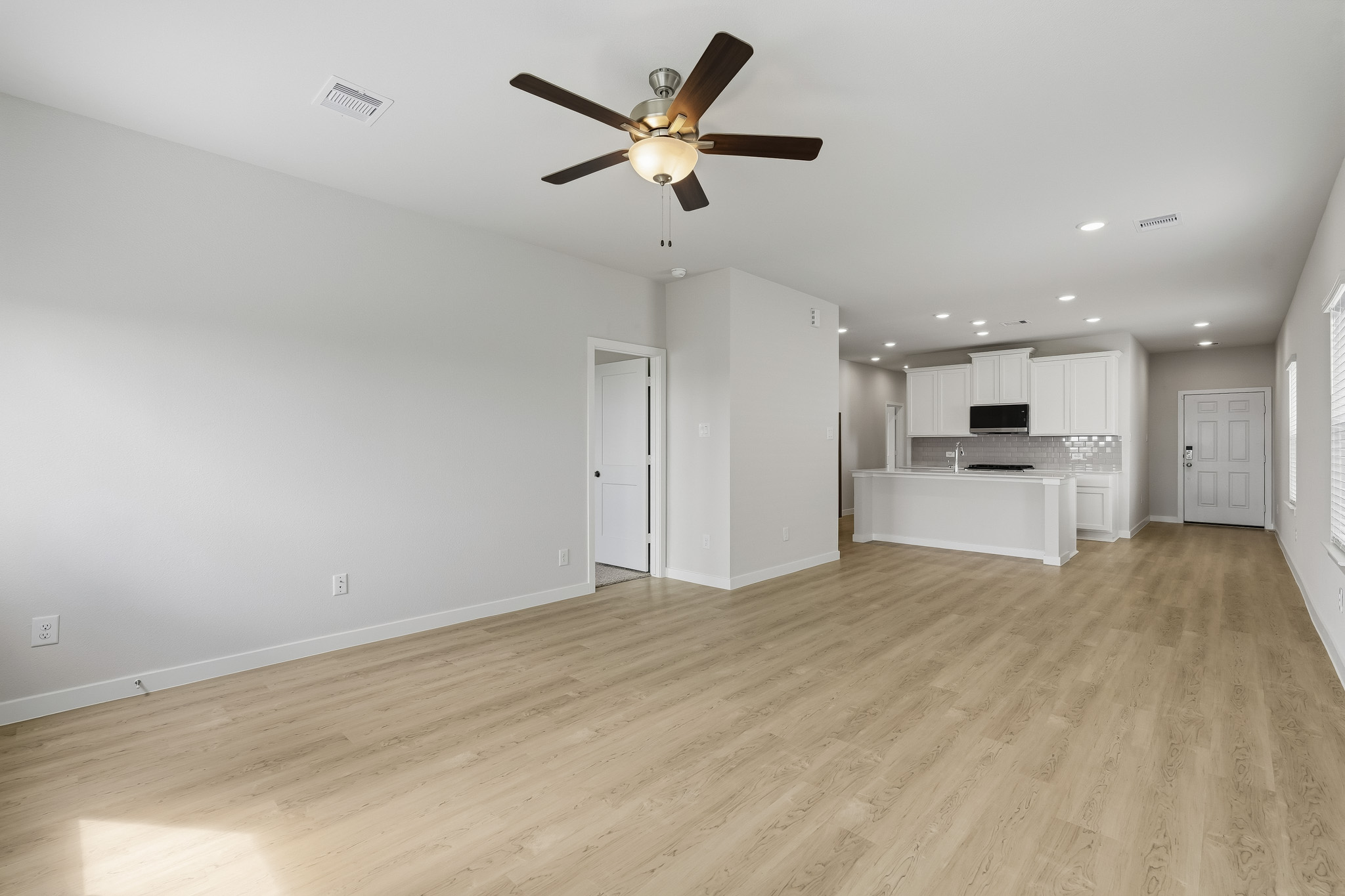 A room with a wood floor and a ceiling fan.