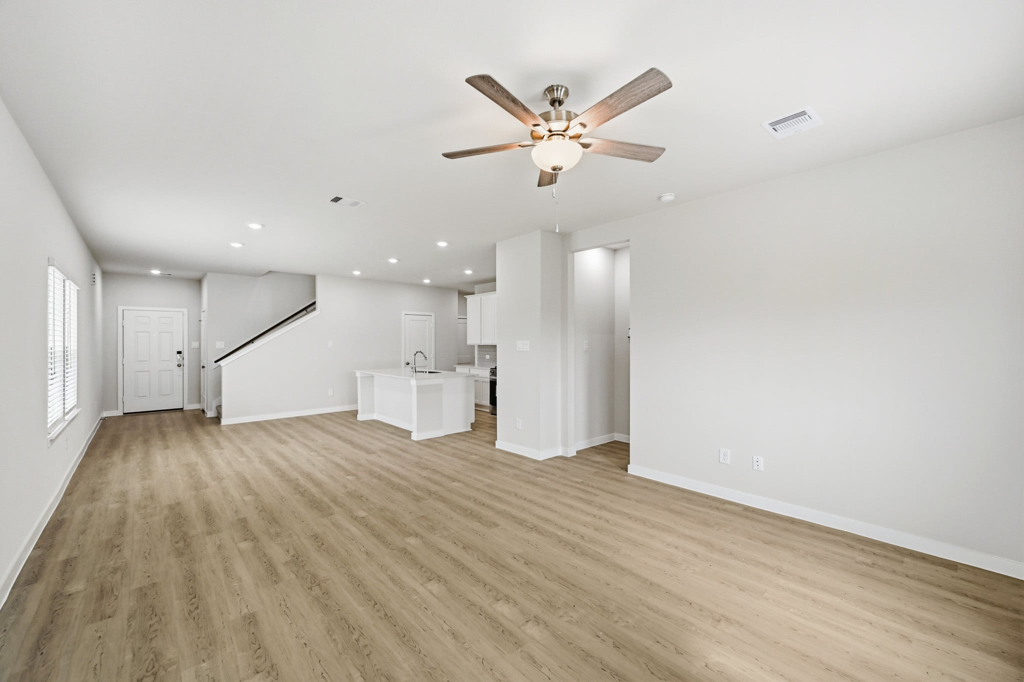 A large empty room with a ceiling fan and a wood floor.