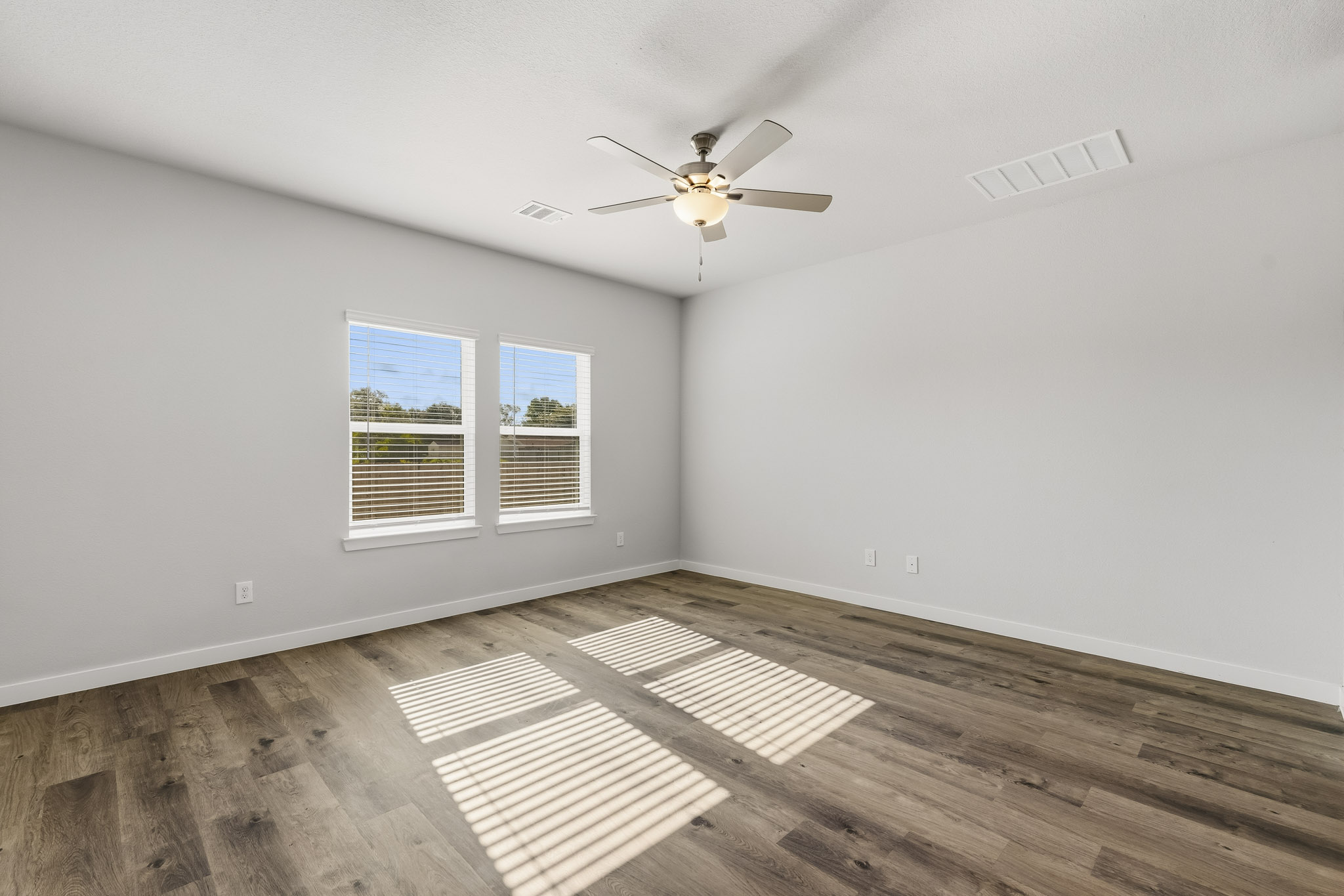 A room with a wood floor and a ceiling fan.