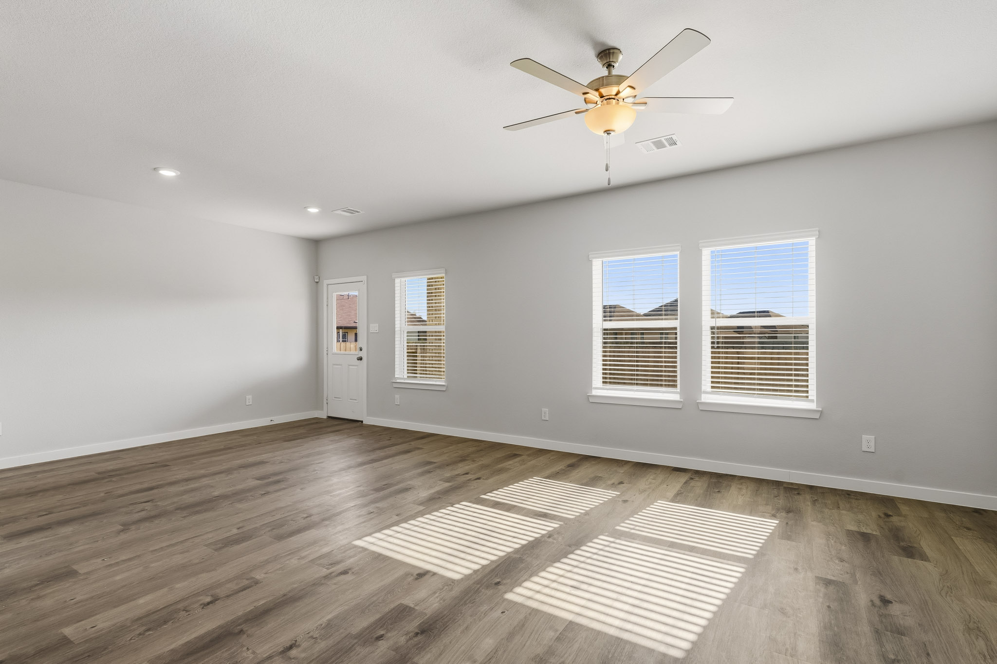 A room with a wood floor and a ceiling fan.