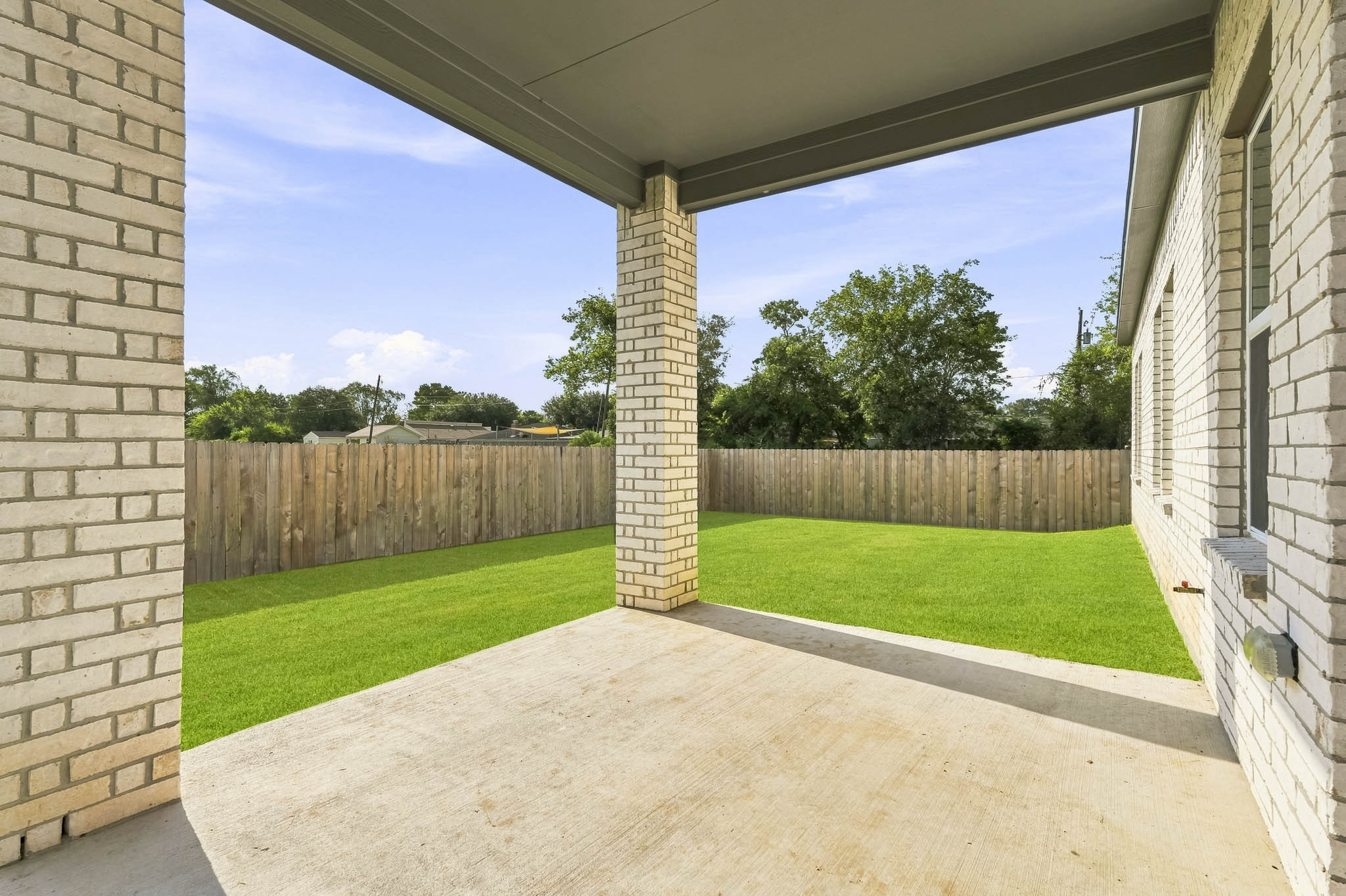 A fenced in yard with a brick wall and a brick building.