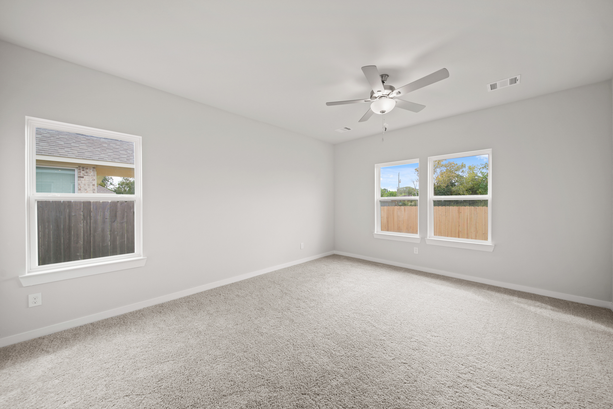 A room with a ceiling fan and windows.