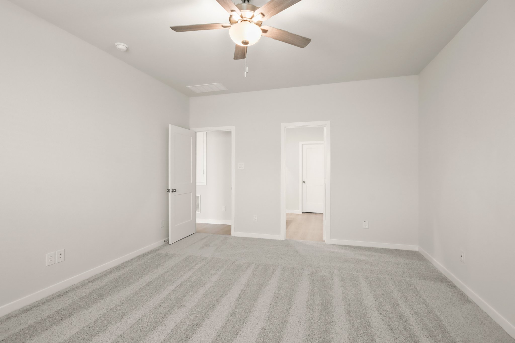 A room with a ceiling fan and white walls.