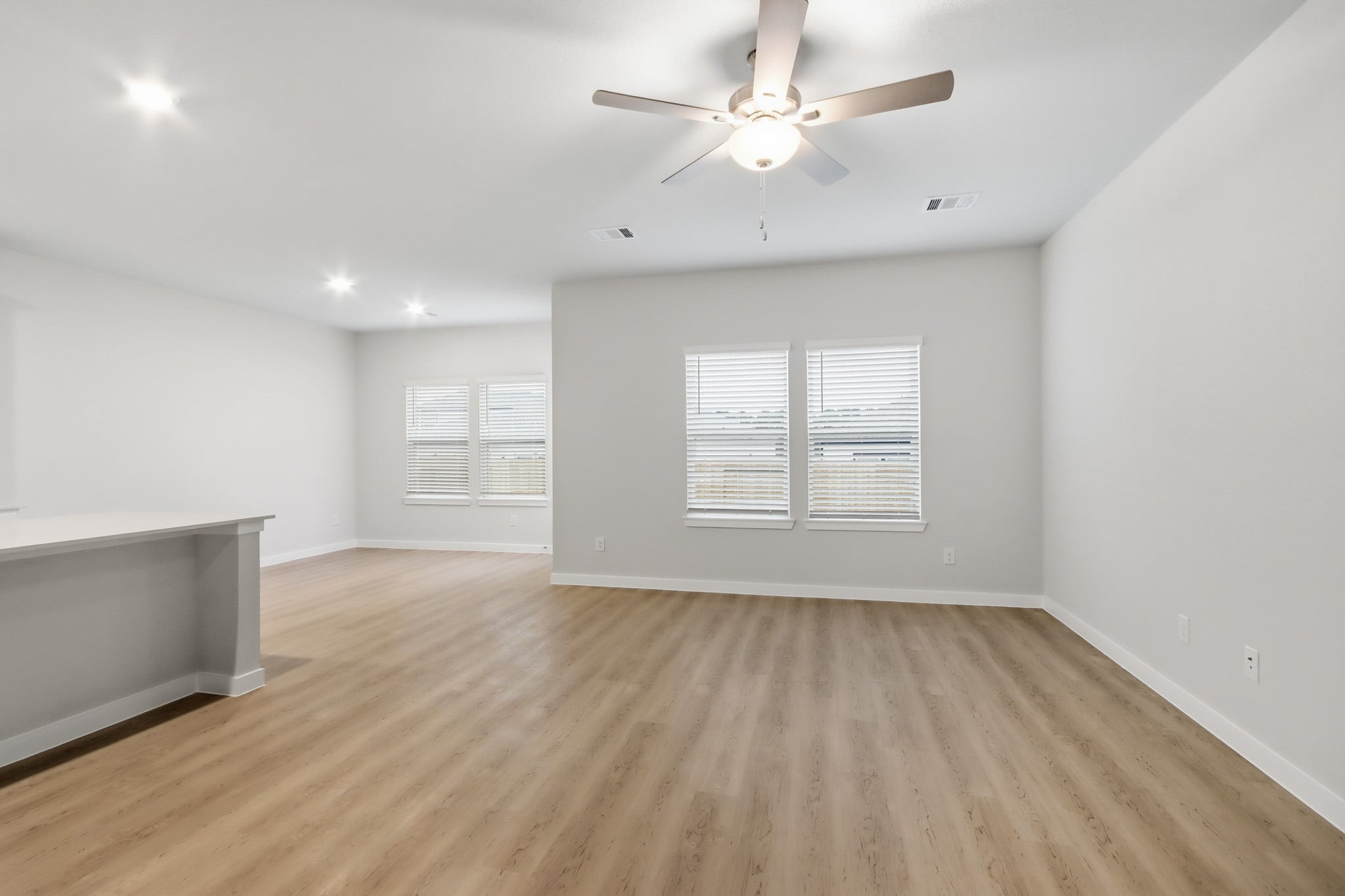 A room with a ceiling fan and a wood floor.