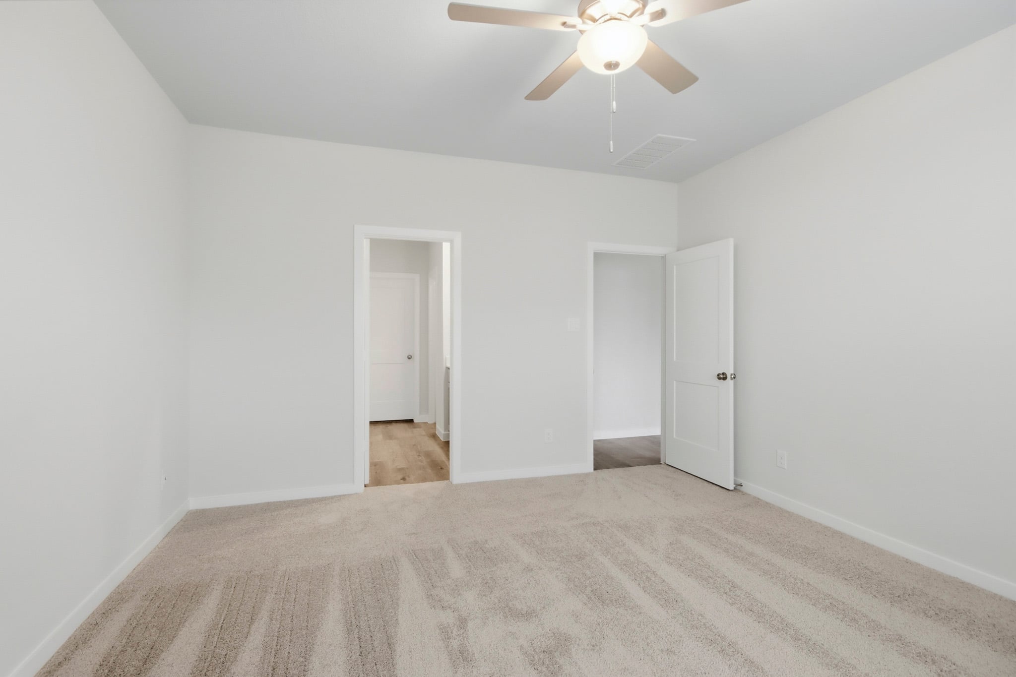 A room with a ceiling fan and a door.