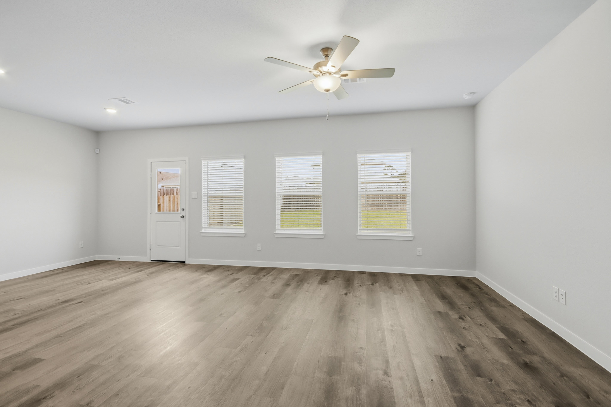 A room with a ceiling fan and a wood floor.