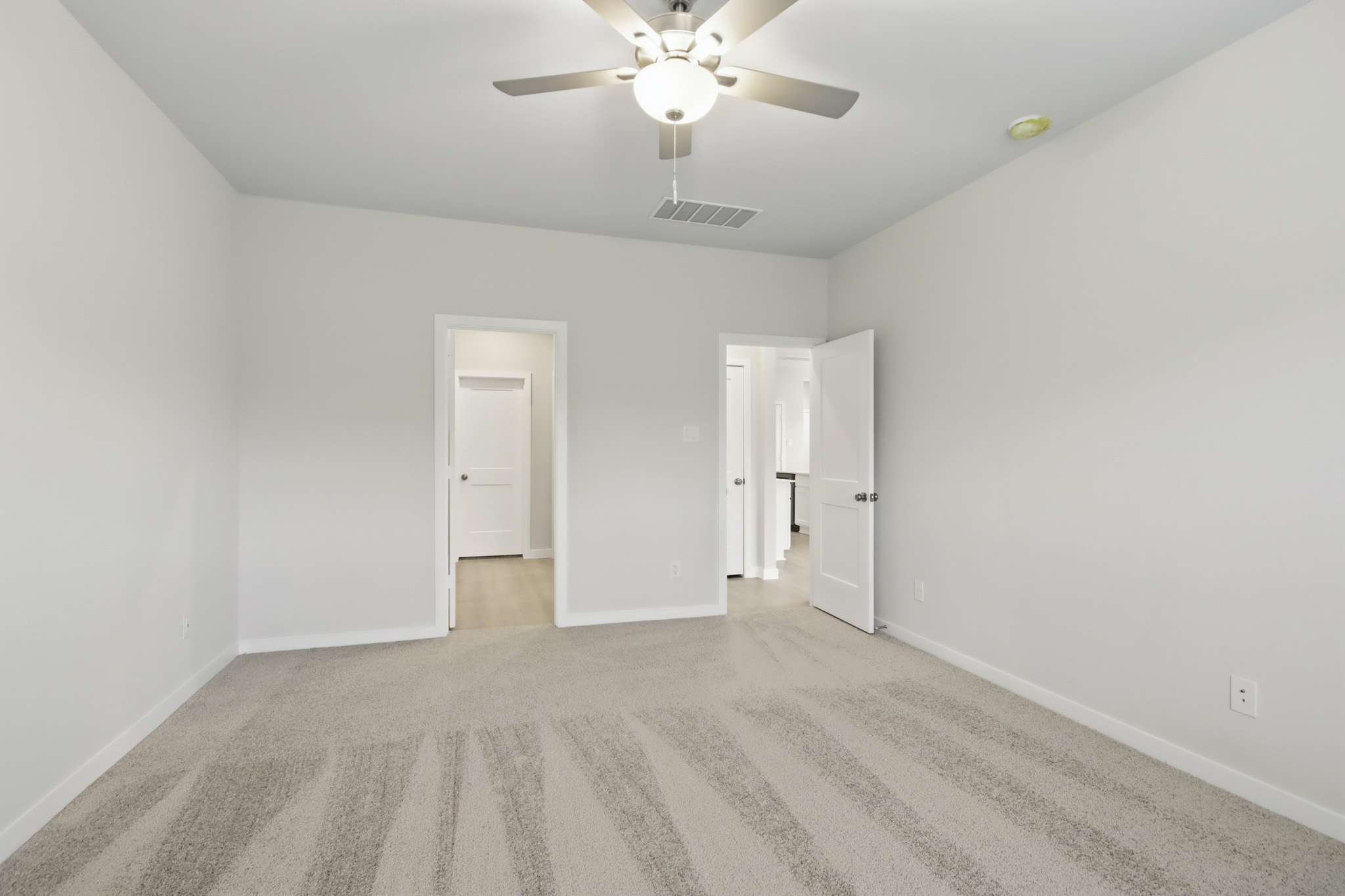 A room with a ceiling fan and a door.