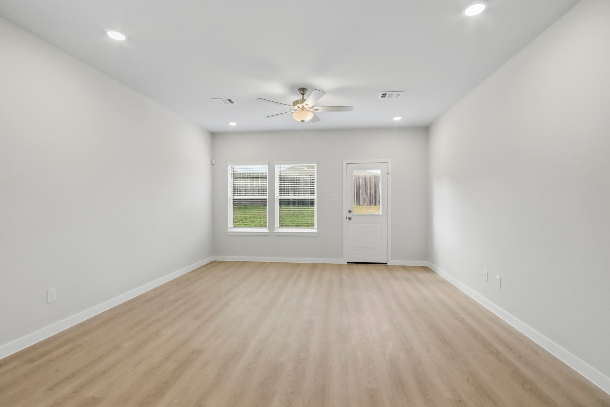 A room with a ceiling fan and a wood floor.